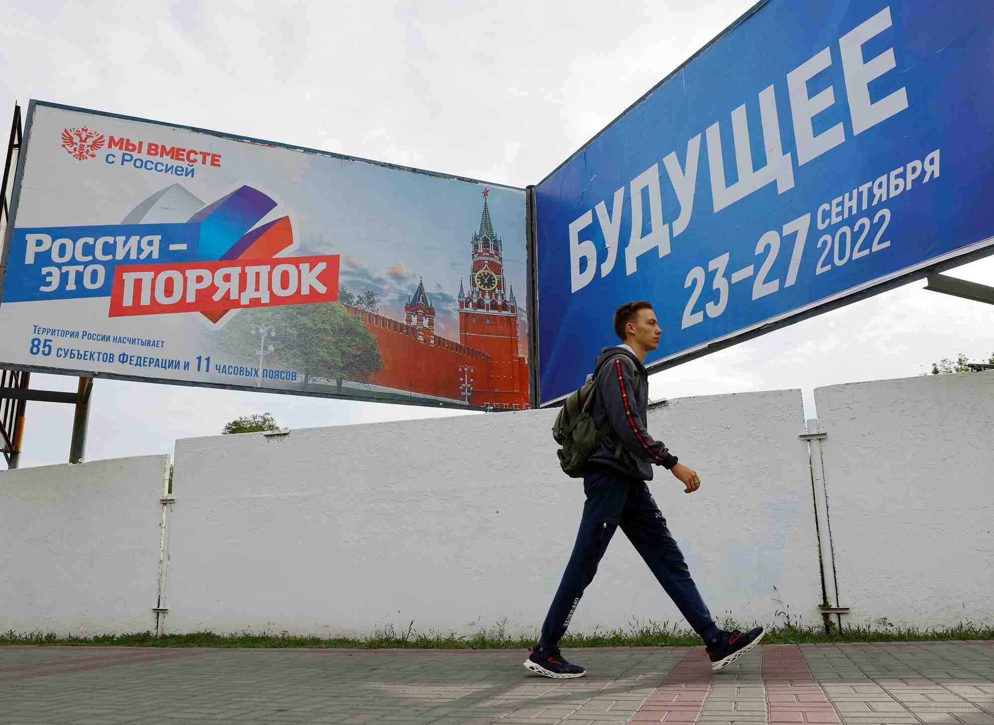 Un homme marche devant des panneaux au sujet d'un referendum sur le rattachement a la russie des regions ukrainiennes controlees par la russie, a melitopol, en ukraine