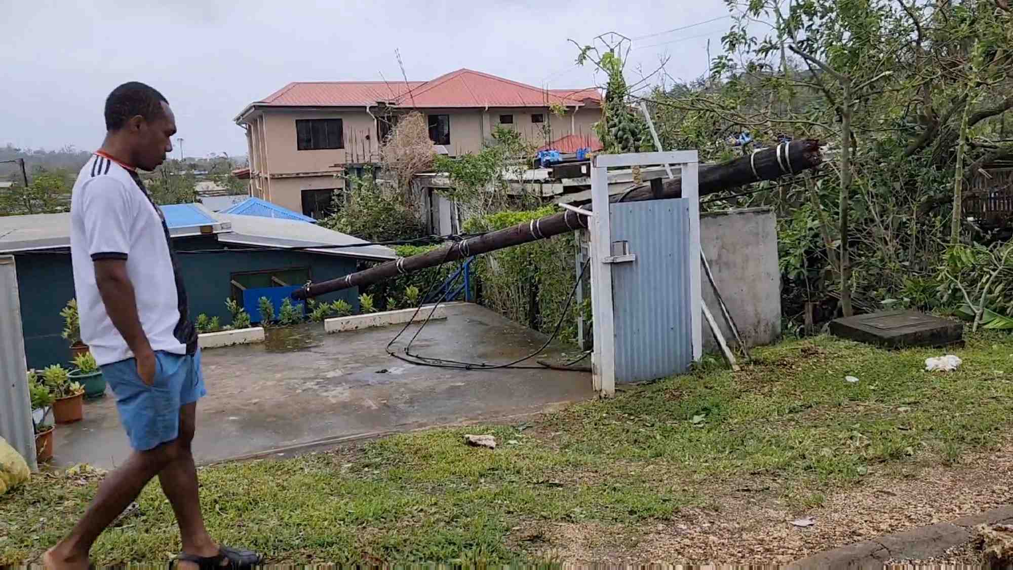 Un homme marche a cote d'un poteau tombe apres le passage du cyclone kevin, a port vila