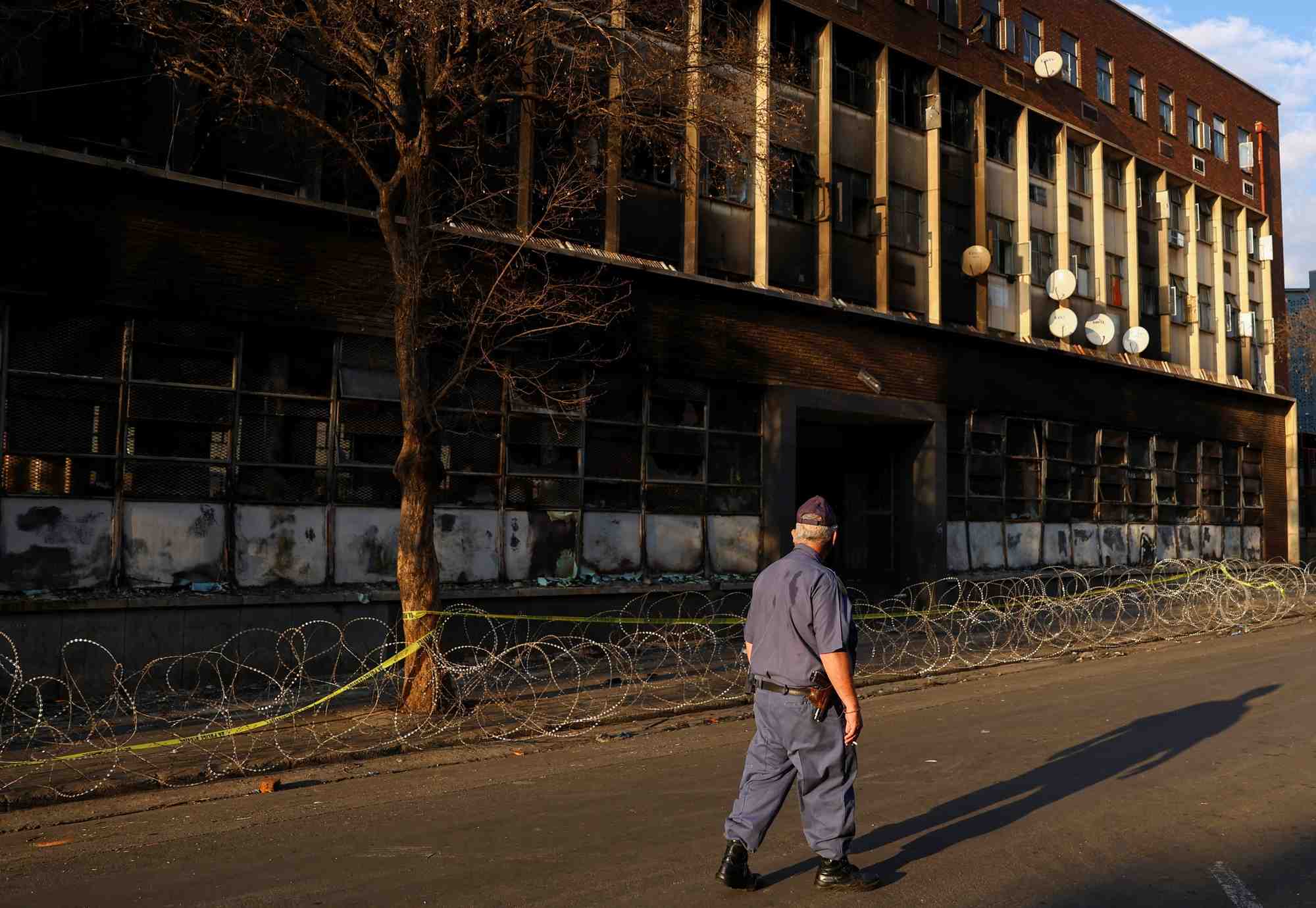 Un policier passe devant l'immeuble ou un incendie meurtrier s'est declare, a johannesburg