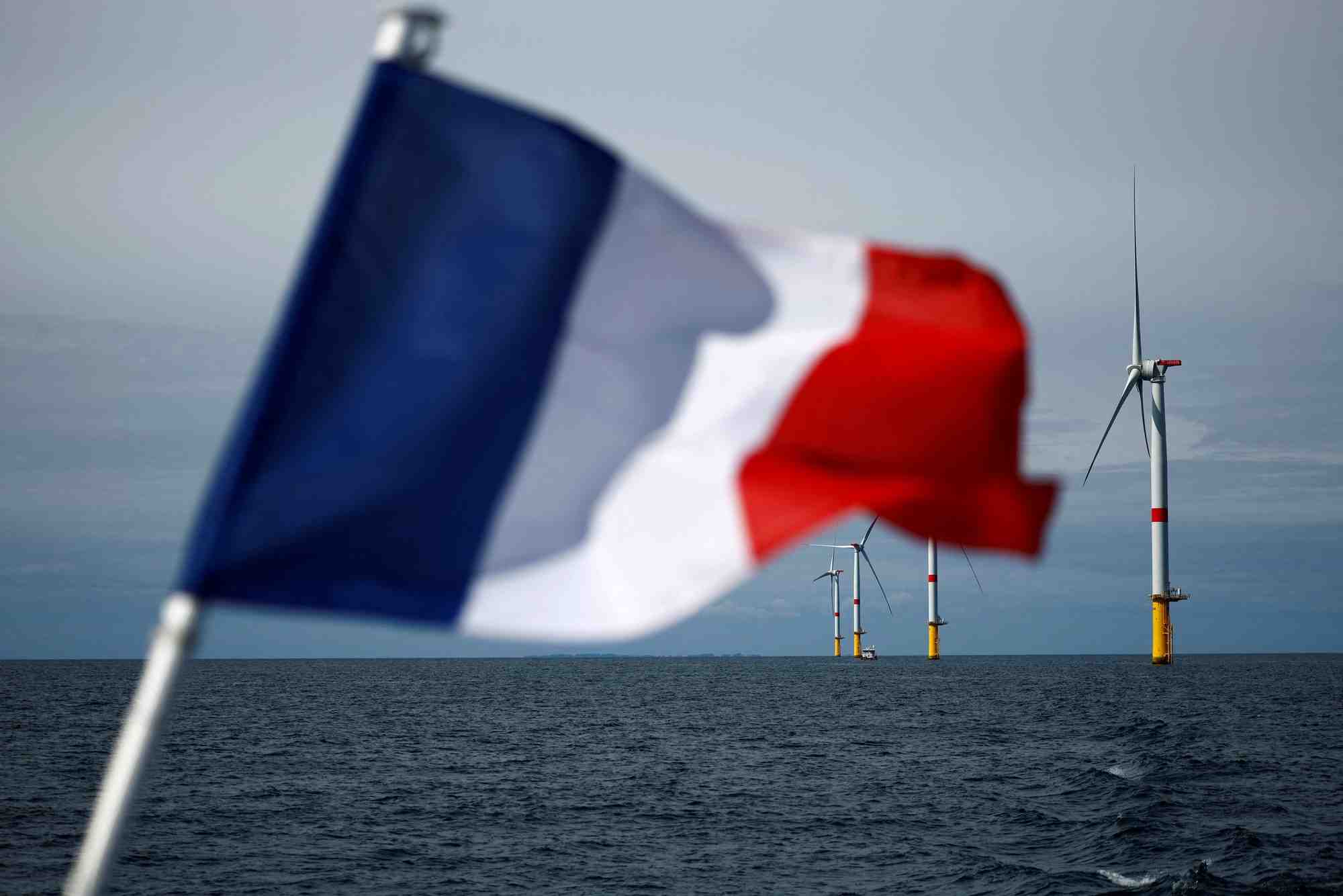 Un drapeau francais devant les eoliennes du parc eolien offshore de saint-nazaire