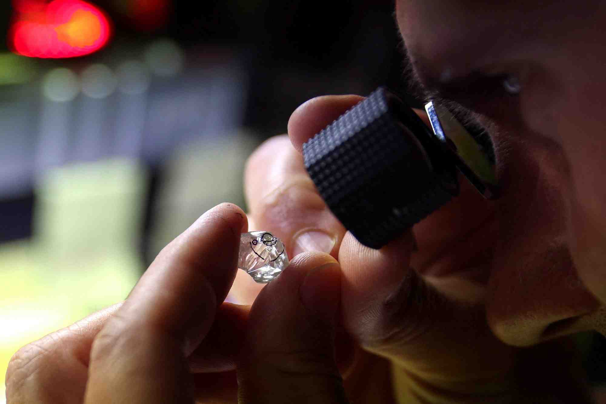 Un employe examine un diamant brut a l'usine "flanders manufacturing"