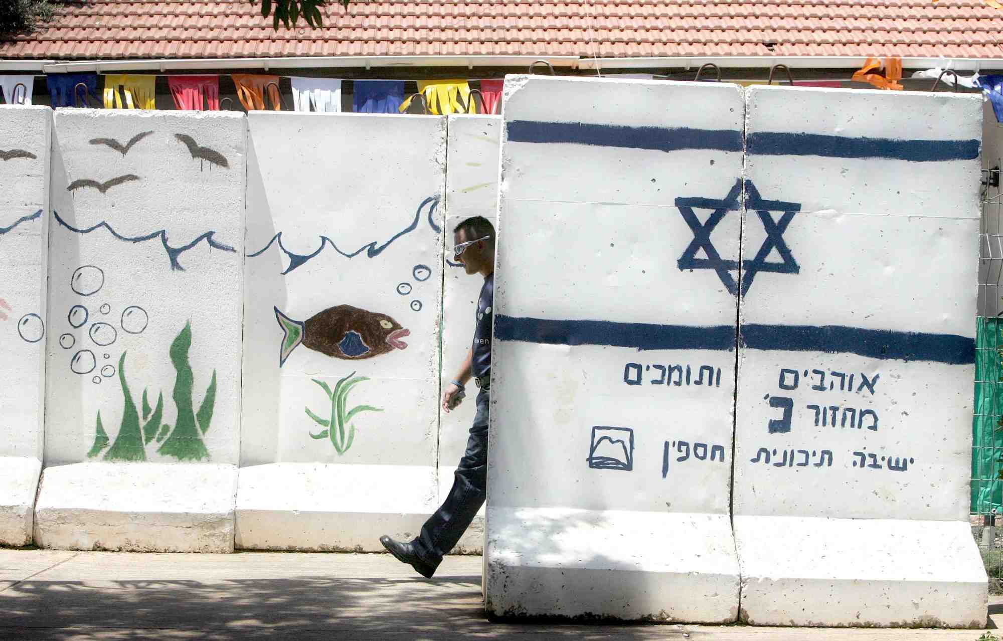 Un colon israelien marche entre des murs de protection en beton dans la colonie de ganim, en cisjordanie