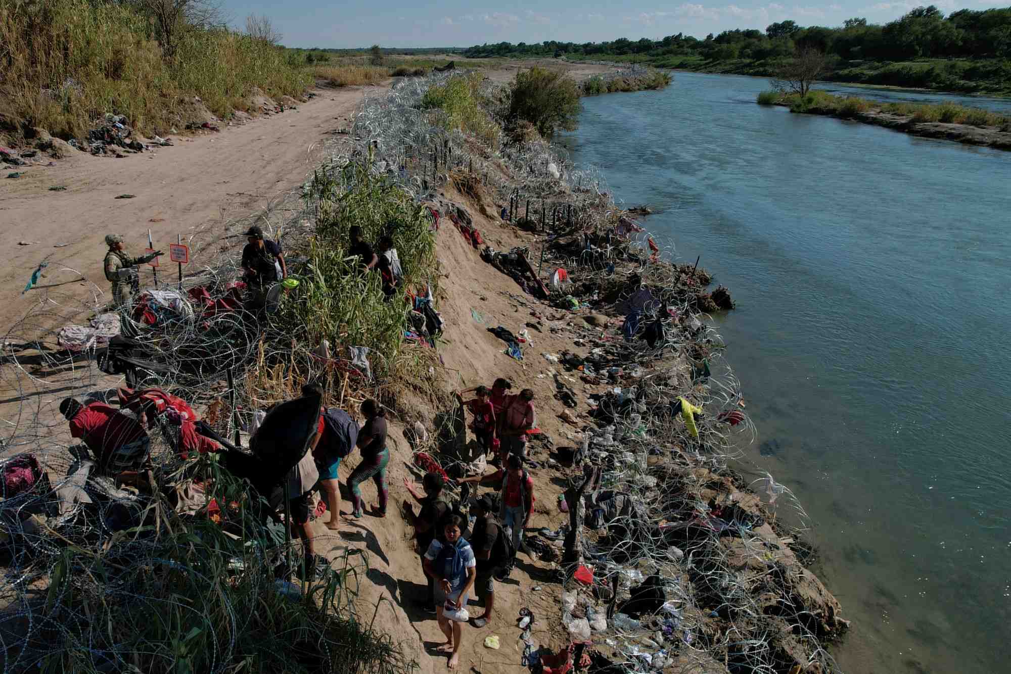 Des membres de la garde nationale du texas tentent de dissuader les migrants de franchir les barbeles apres avoir traverse le rio grande