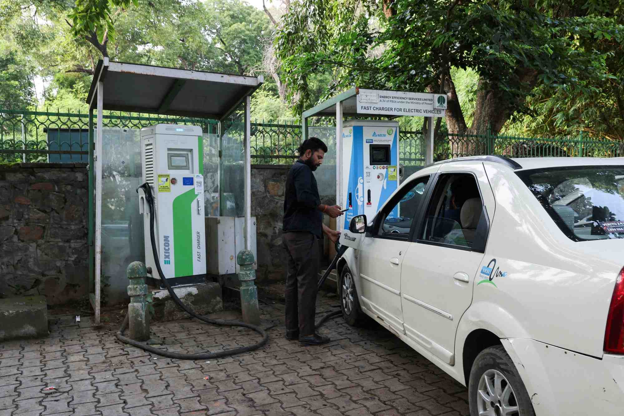 Un homme charge sa voiture electrique a new delhi, en inde