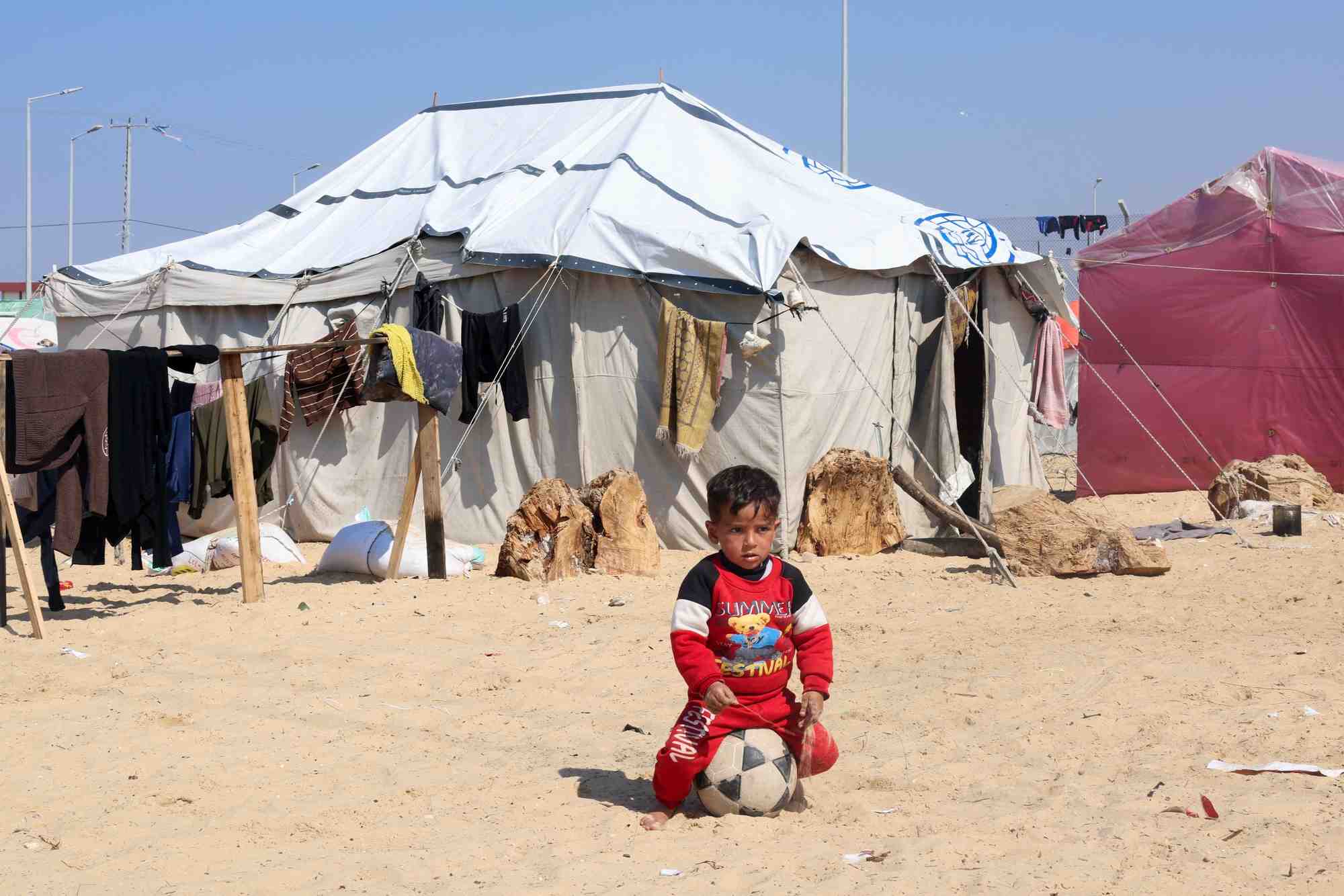 Un garcon palestinien deplace, qui a fui sa maison a cause des frappes israeliennes, est assis sur un ballon a rafah