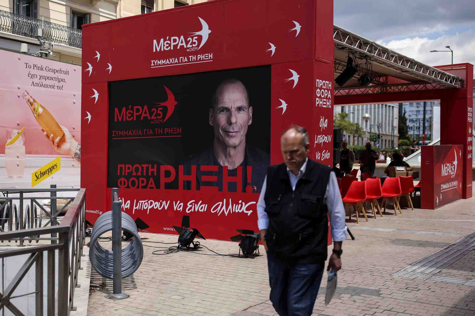 Photo d'un homme qui passe devant le kiosque pre-electoral du parti mera25 a athenes