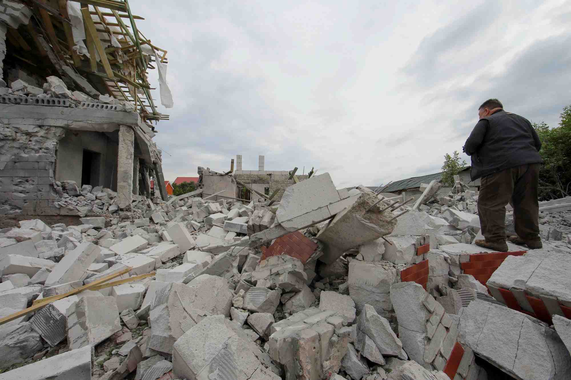 Photo d'un homme qui se tient debout sur les debris d'un batiment fortement endommage par une frappe militaire russe