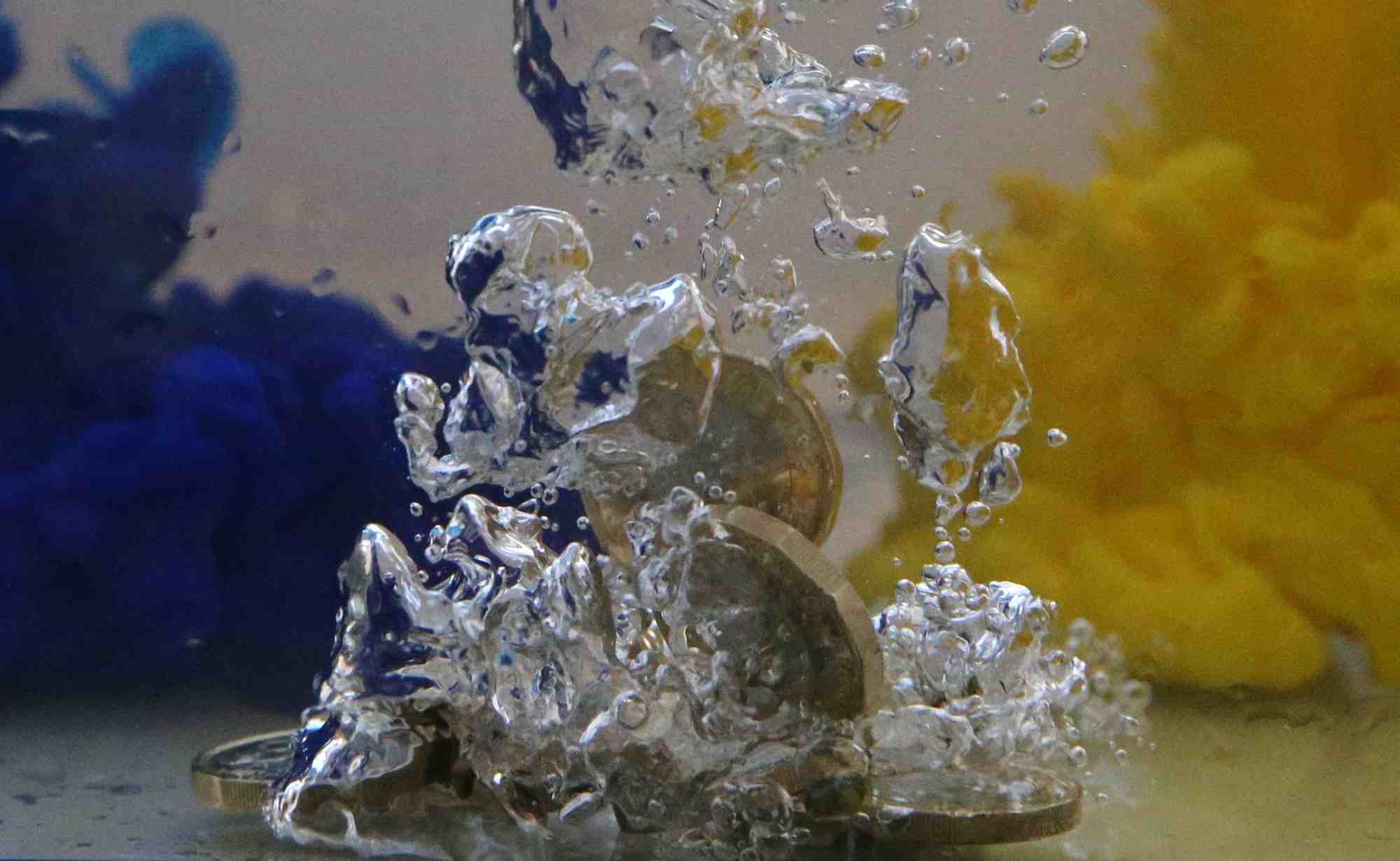 Des pieces de monnaie en livres sterling dans de l'eau aux couleurs du drapeau de l'union europeenne