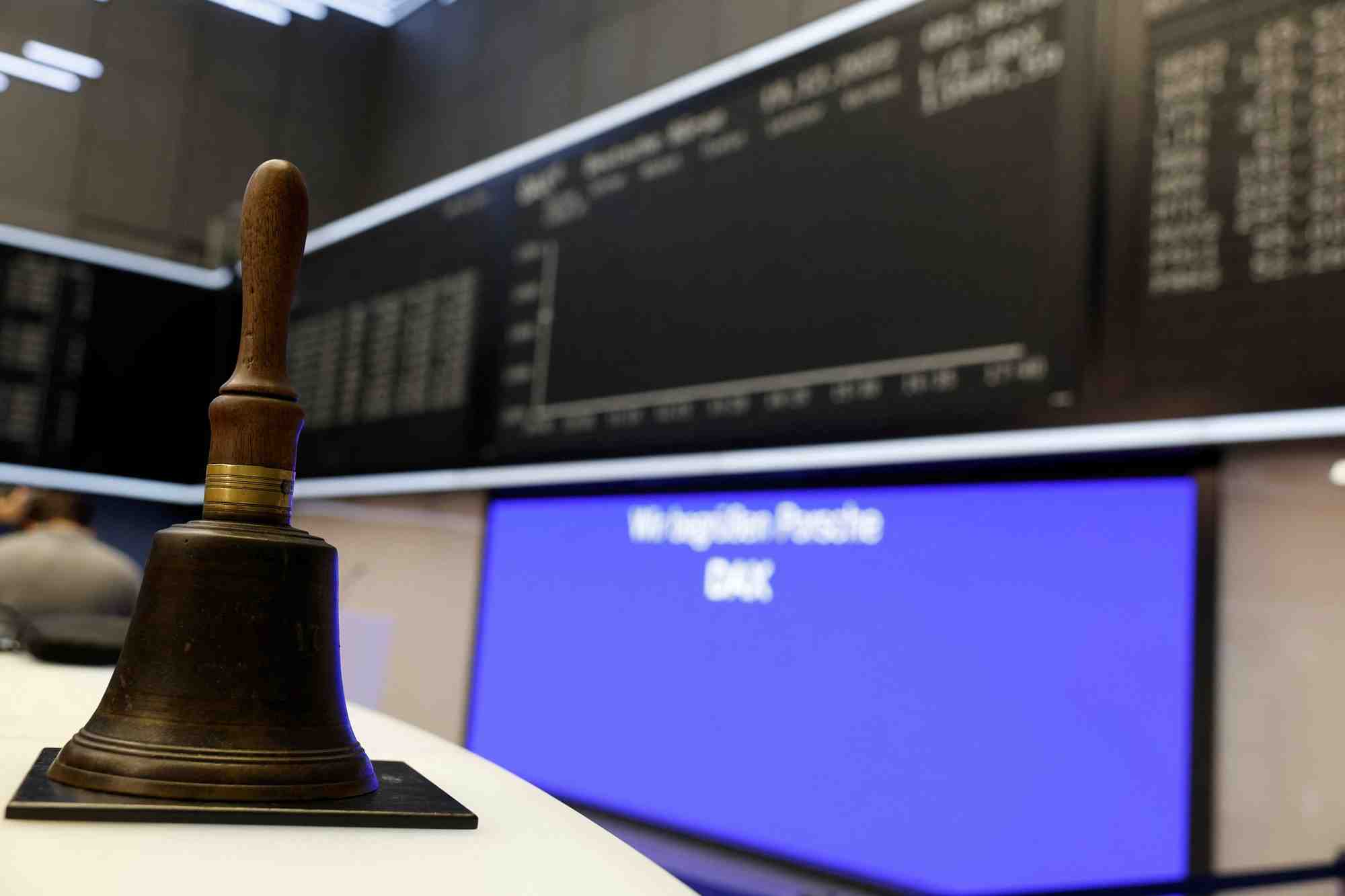Photo d'une cloche qui est placee devant un ecran de l'indice allemand dax a la bourse de francfort