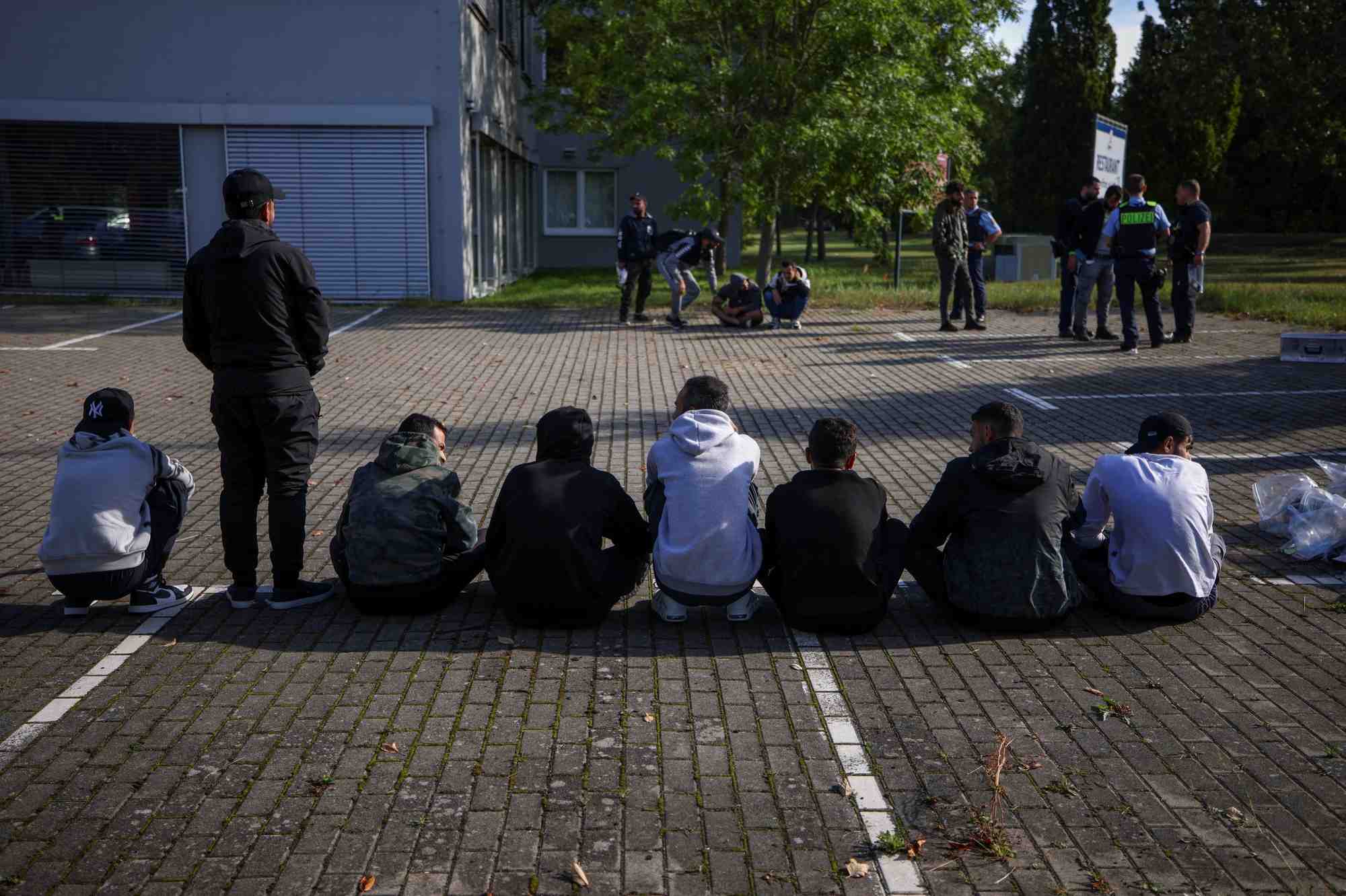 Des migrants sont assis par terre apres avoir ete arretes par la police allemande