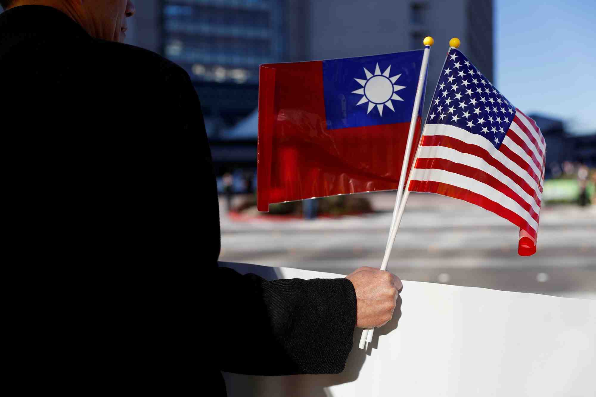 Photo d'un homme qui tient des drapeau de taiwan et des etats-unis