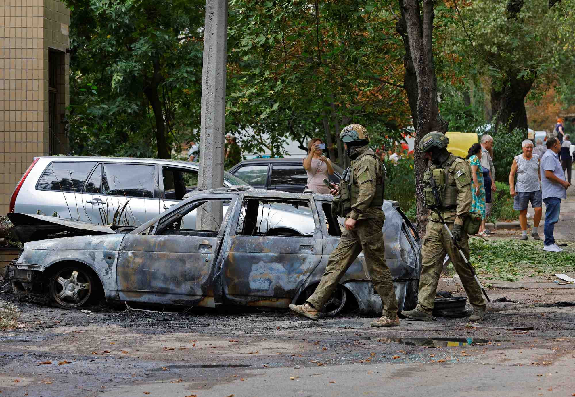 Des soldats russes marchent pres d'une voiture endommagee a donetsk