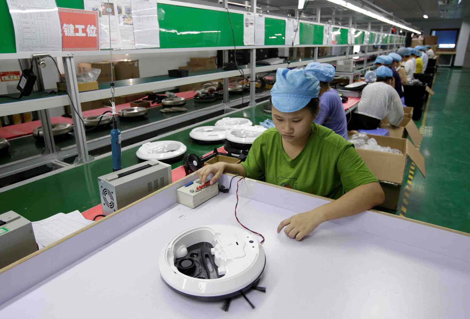 Photo d'archives: une employee travaille sur la ligne de production d'une usine d'aspirateurs robots de matsutek a shenzhen