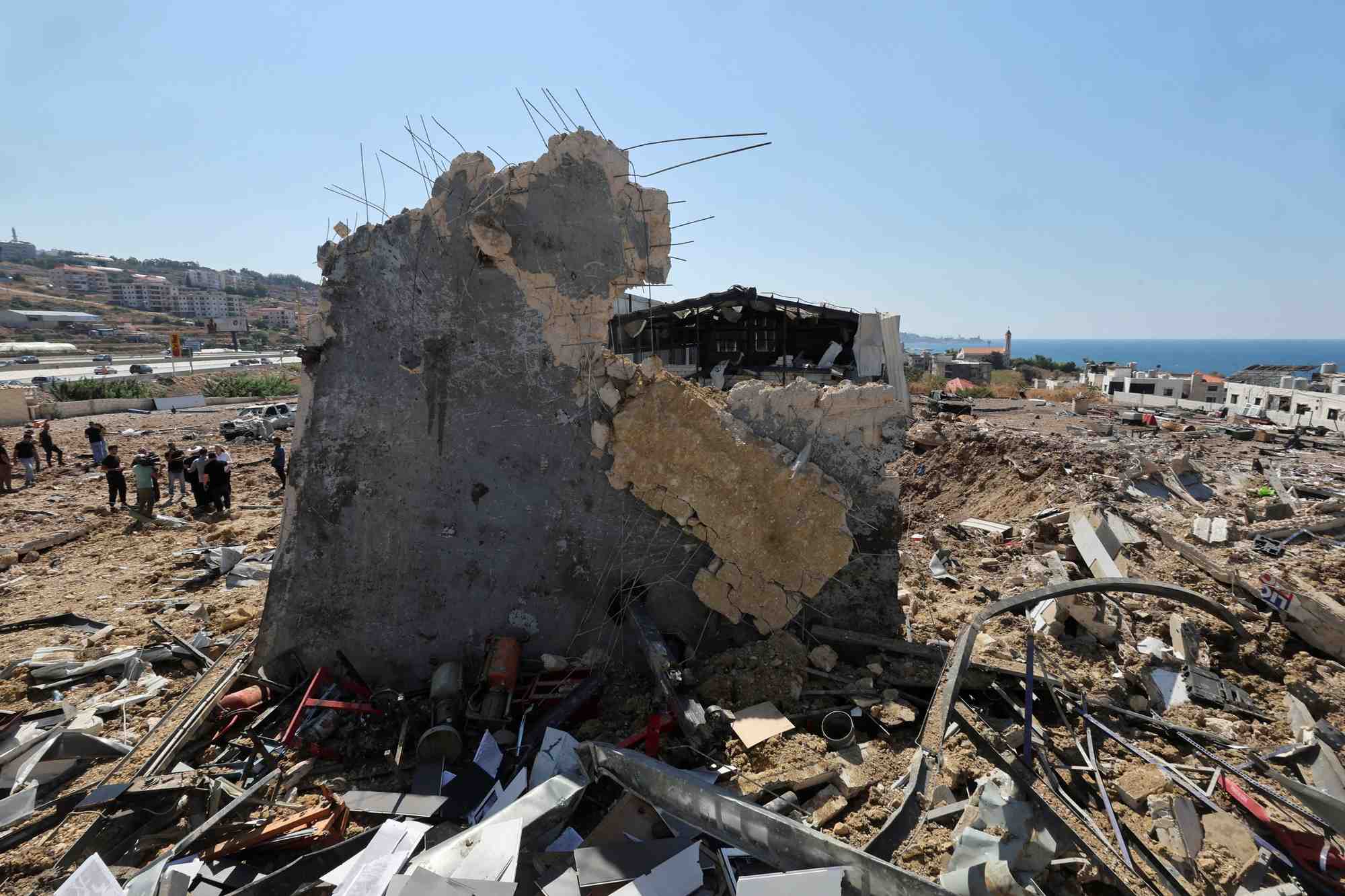 Des personnes inspectent les degats sur le site d'une frappe israelienne qui a touche la ville balneaire libanaise de jiyeh