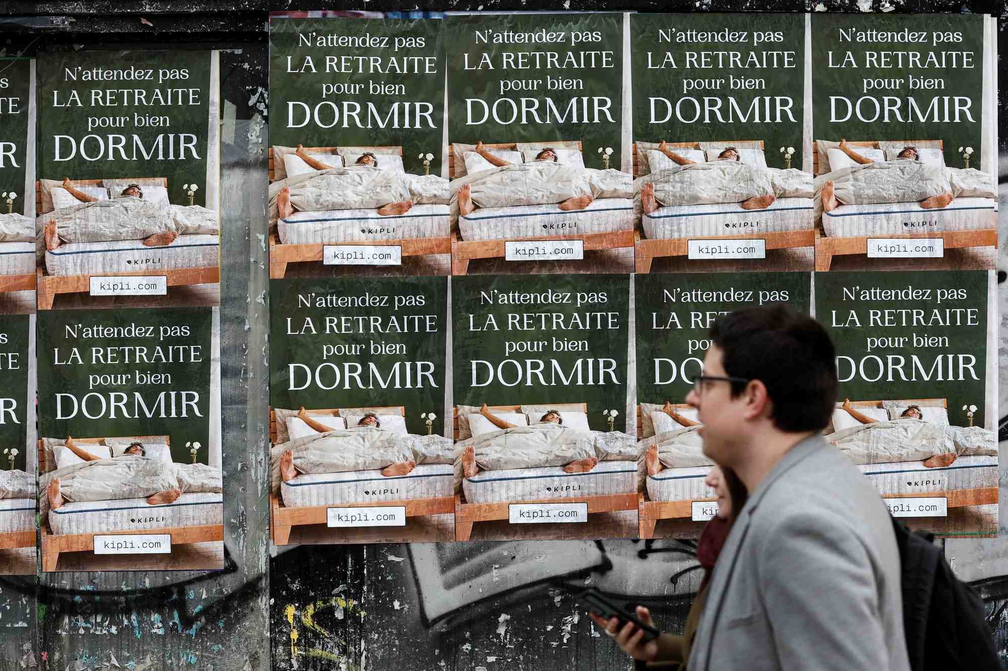 Des gens passent devant des affiches a paris protestant contre le plan de reforme des retraites en france