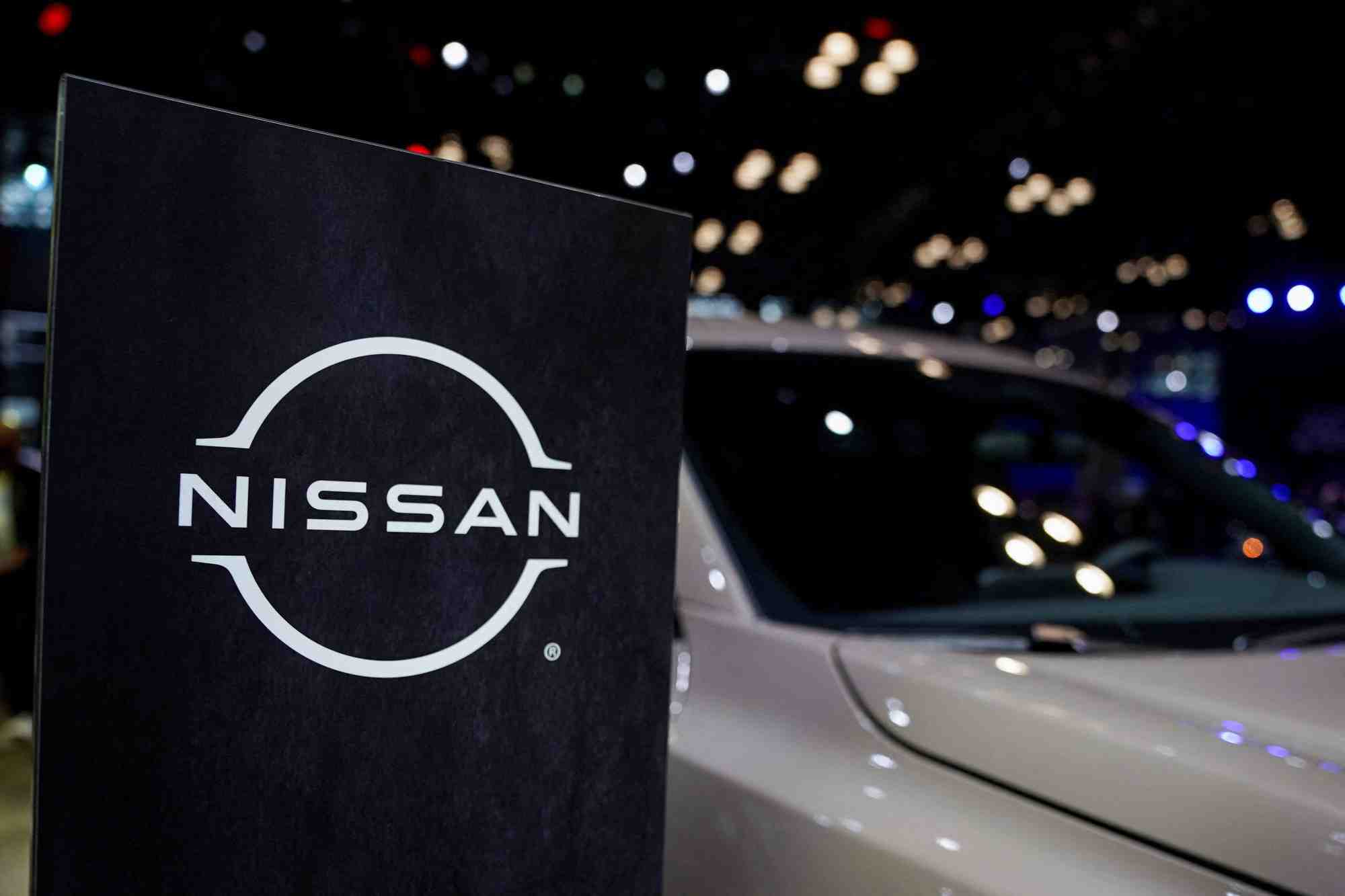 Un logo nissan est visible a cote d'un vehicule lors du salon international de l'automobile de new york