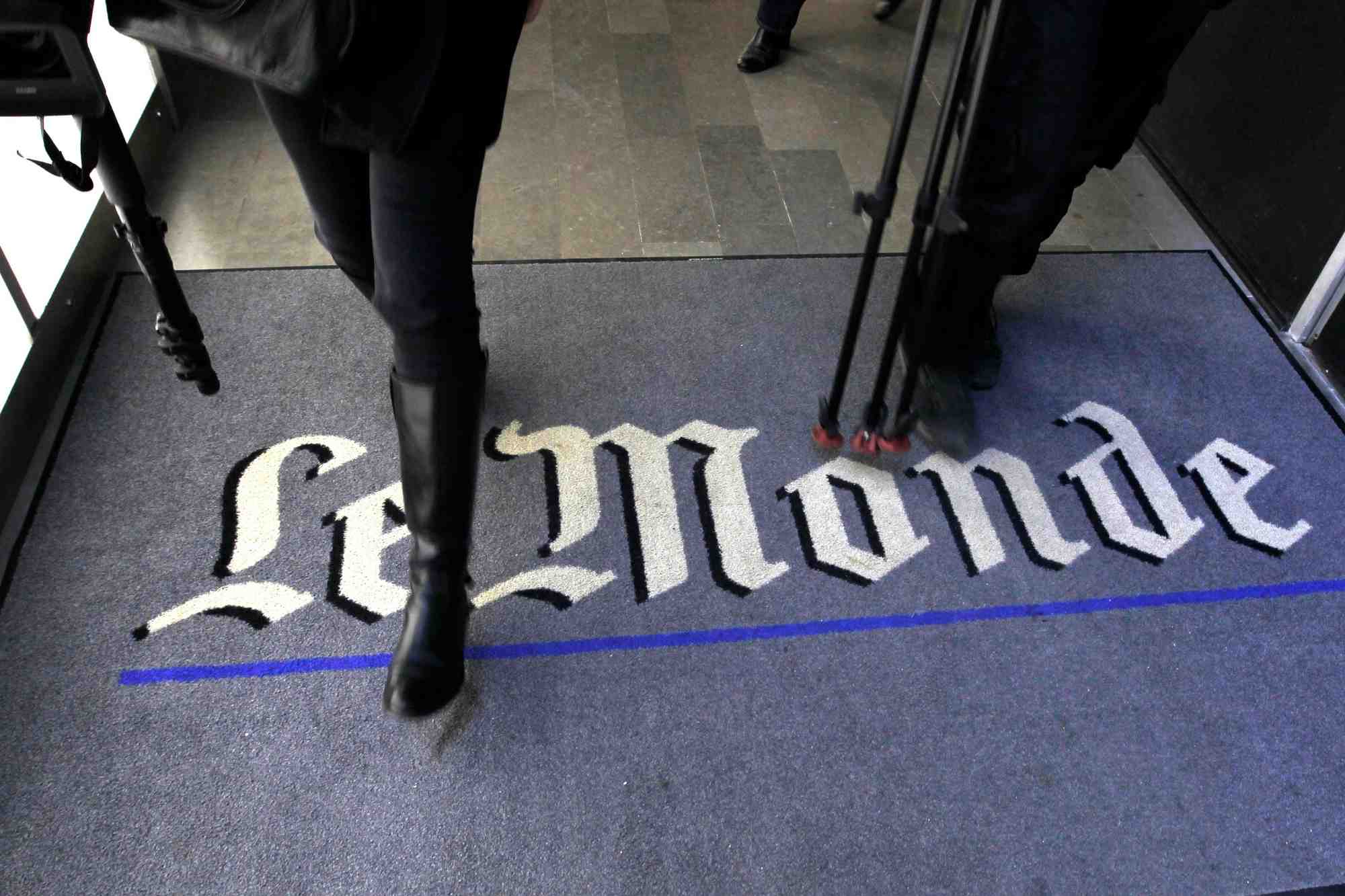 Un journaliste marche sur le logo du quotidien francais le monde dans leurs bureaux a paris