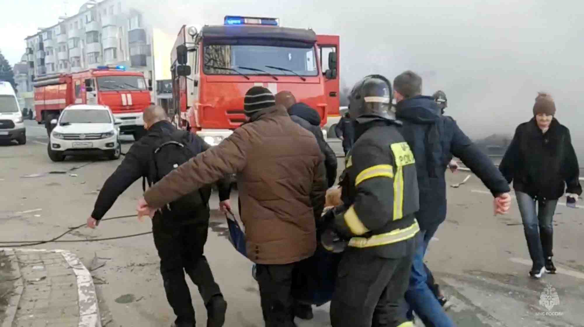 Des personnes, dont des pompiers, transportent une personne hors du site apres un bombardement a belgorod