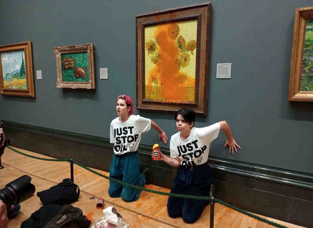 Des membres du mouvement ecologiste "just stop oil" collent leurs mains au mur apres avoir jete de la soupe sur "les tournesols" de vincent van gogh a la national gallery de londres