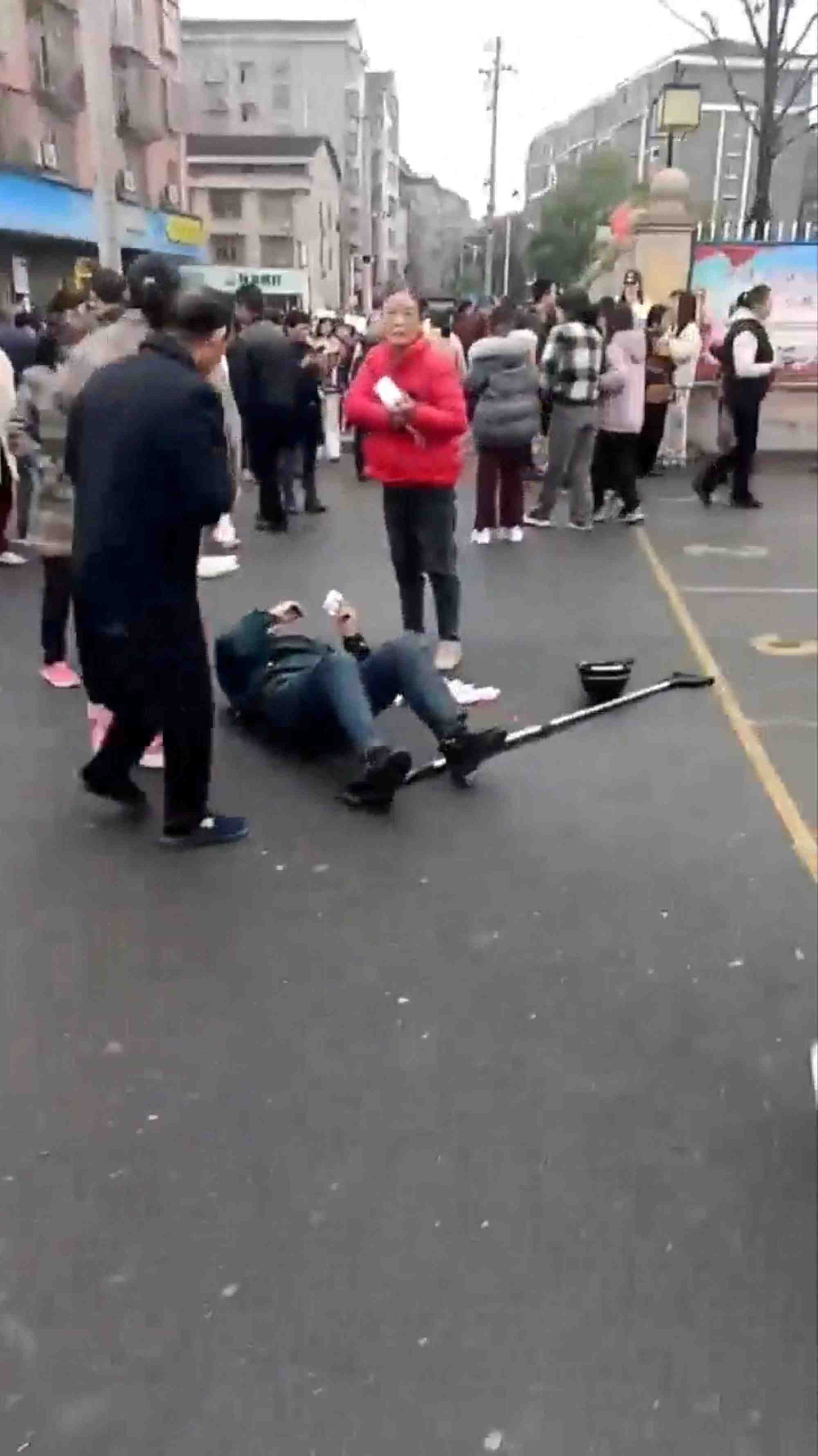 Une personne git au sol apres une collision de vehicule devant une ecole primaire en chine