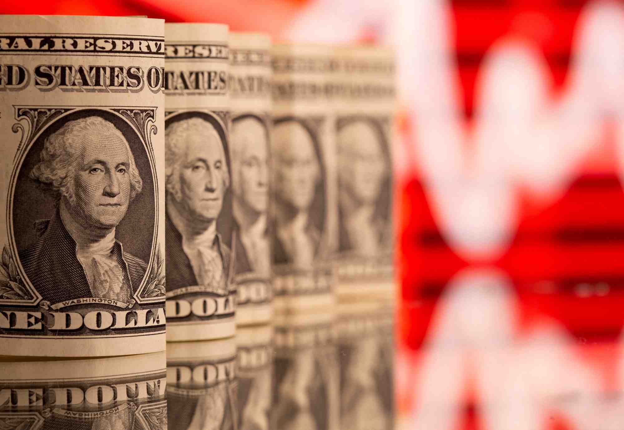 Photo d'illustration montrant des billets de banque americains d'un dollar devant un graphique boursier