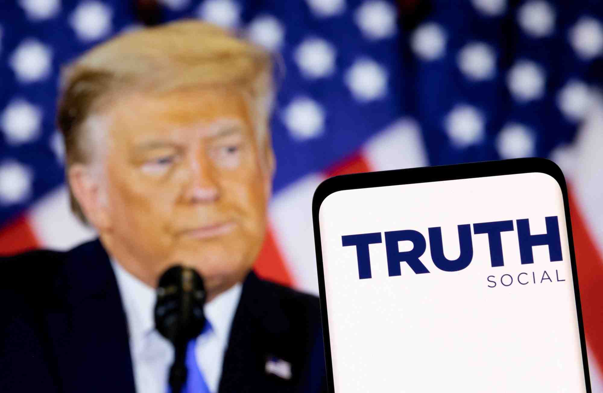 Le logo du reseau social truth est visible sur un smartphone devant une image de donald trump