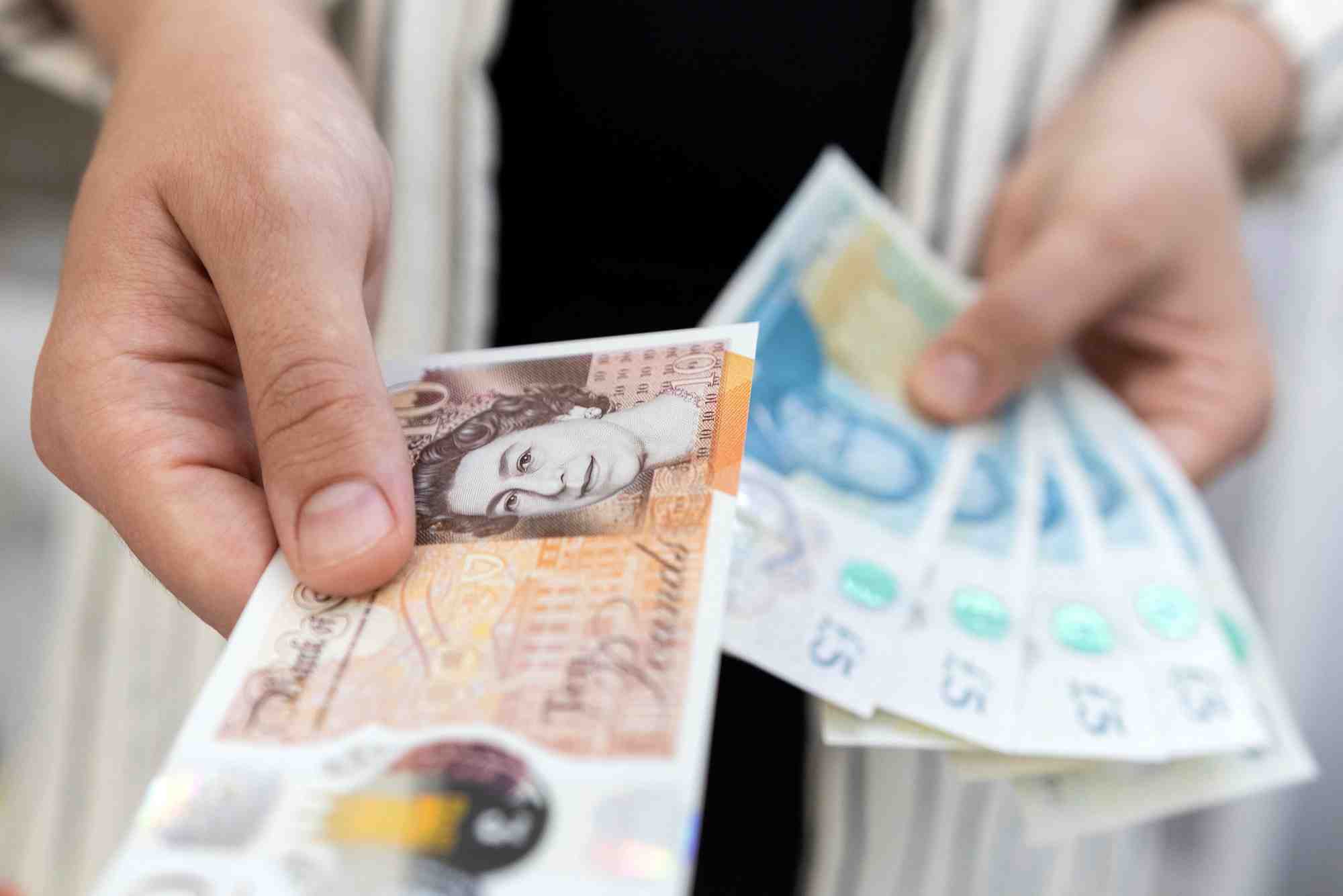 Photo d'illustration d'une femme tenant des billets de banque en livres sterling