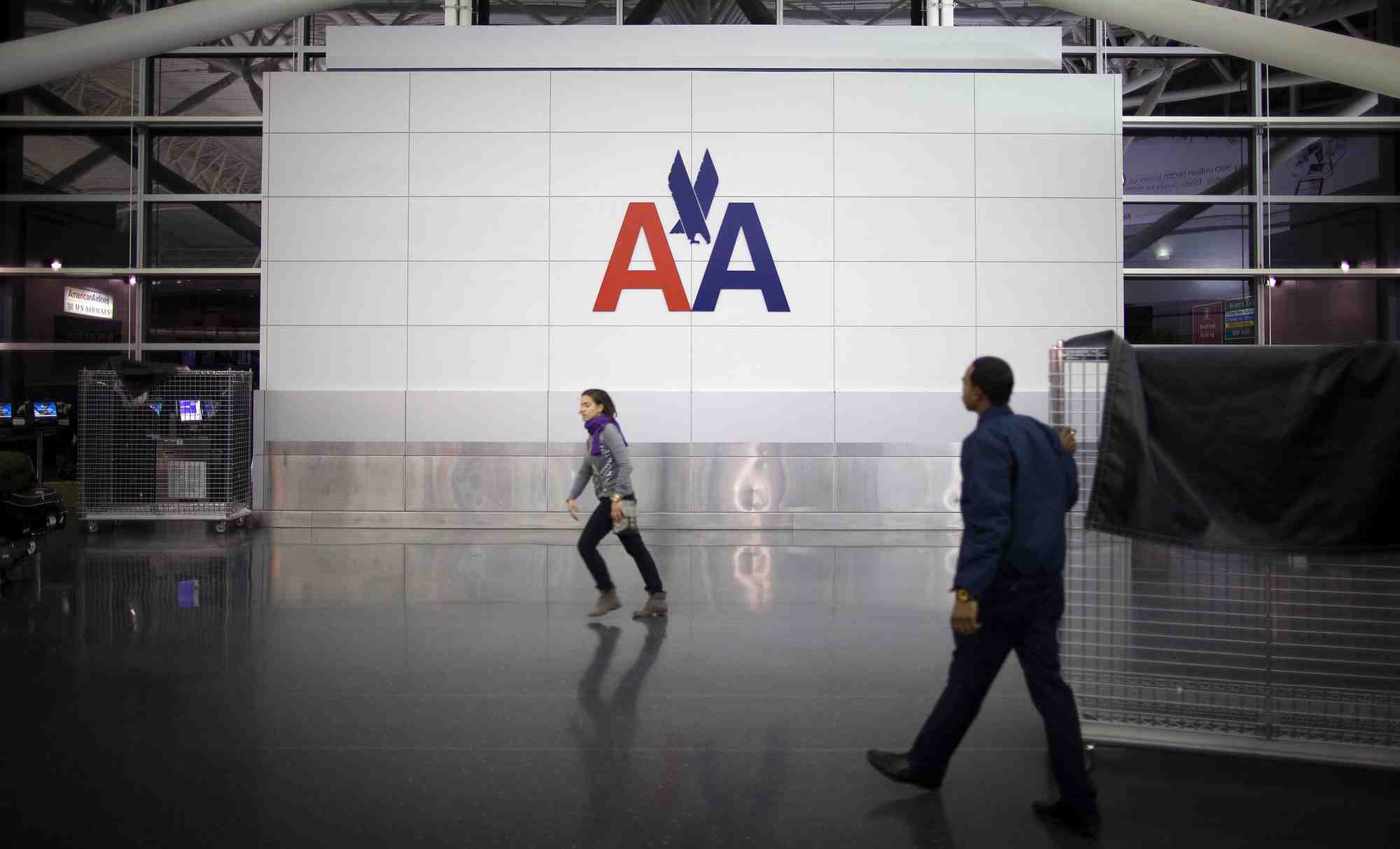 Des personnes passent devant le logo d'american airlines a l'aeroport john f. kennedy (jfk) de new york