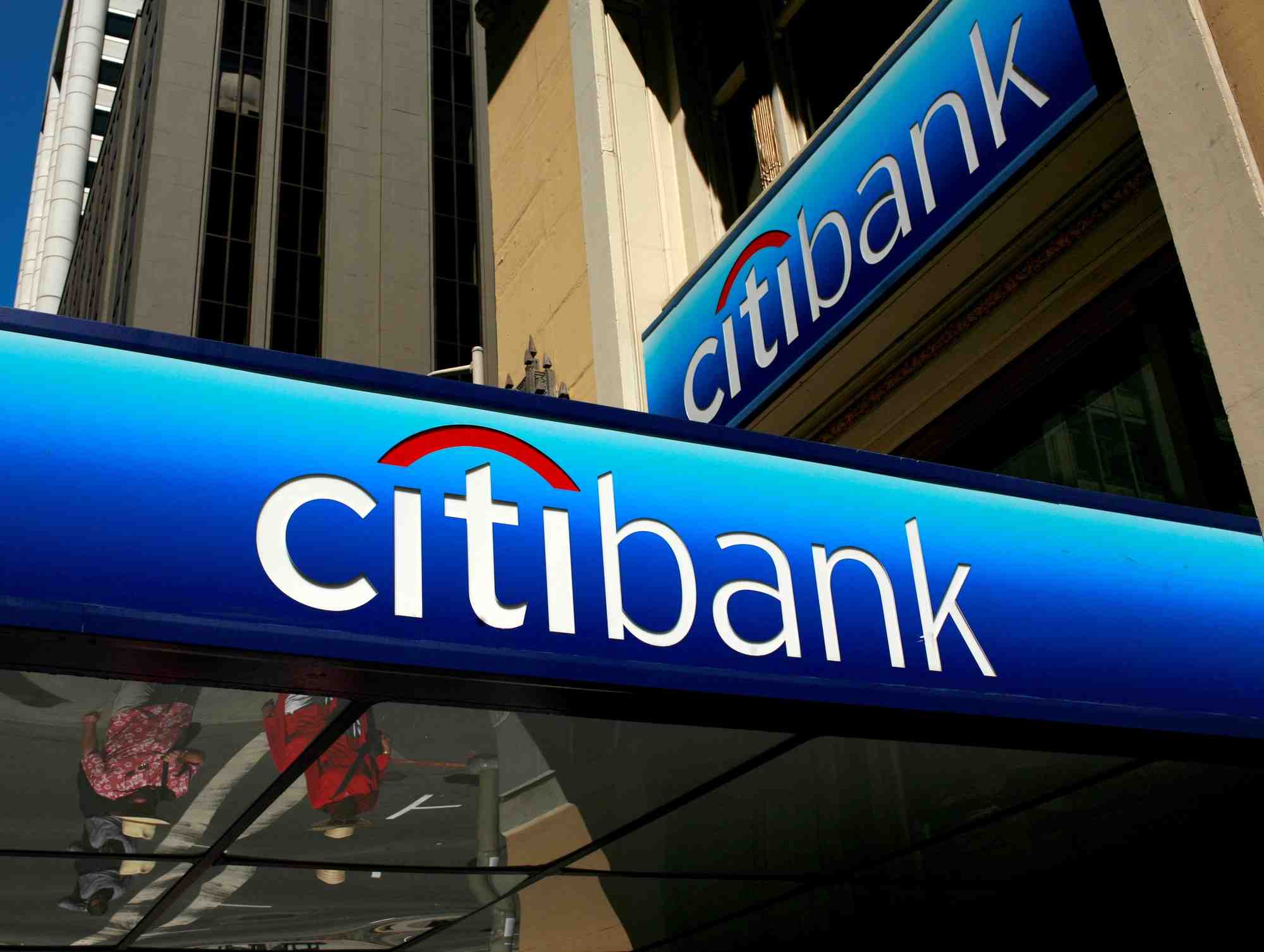 Des personnes marchent sous le logo d'une succursale de la citibank dans le quartier financier de san francisco, en californie