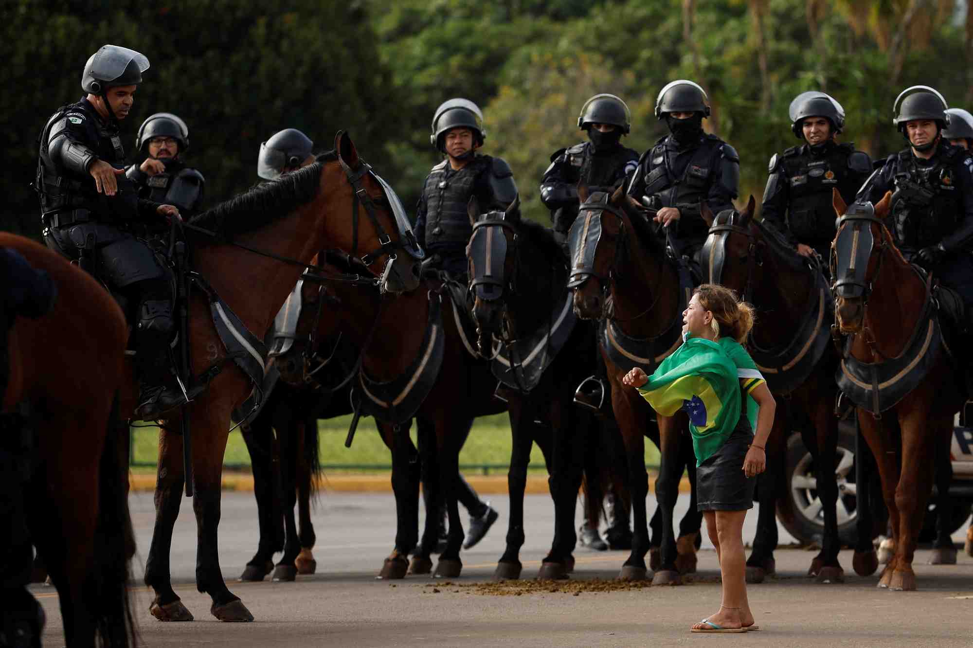 Un manifestant et des membres des forces de securite pendant le demantelement d'un camp de partisans de l'ancien president bresilien jair bolsonaro devant le siege de l'armee, a brasilia