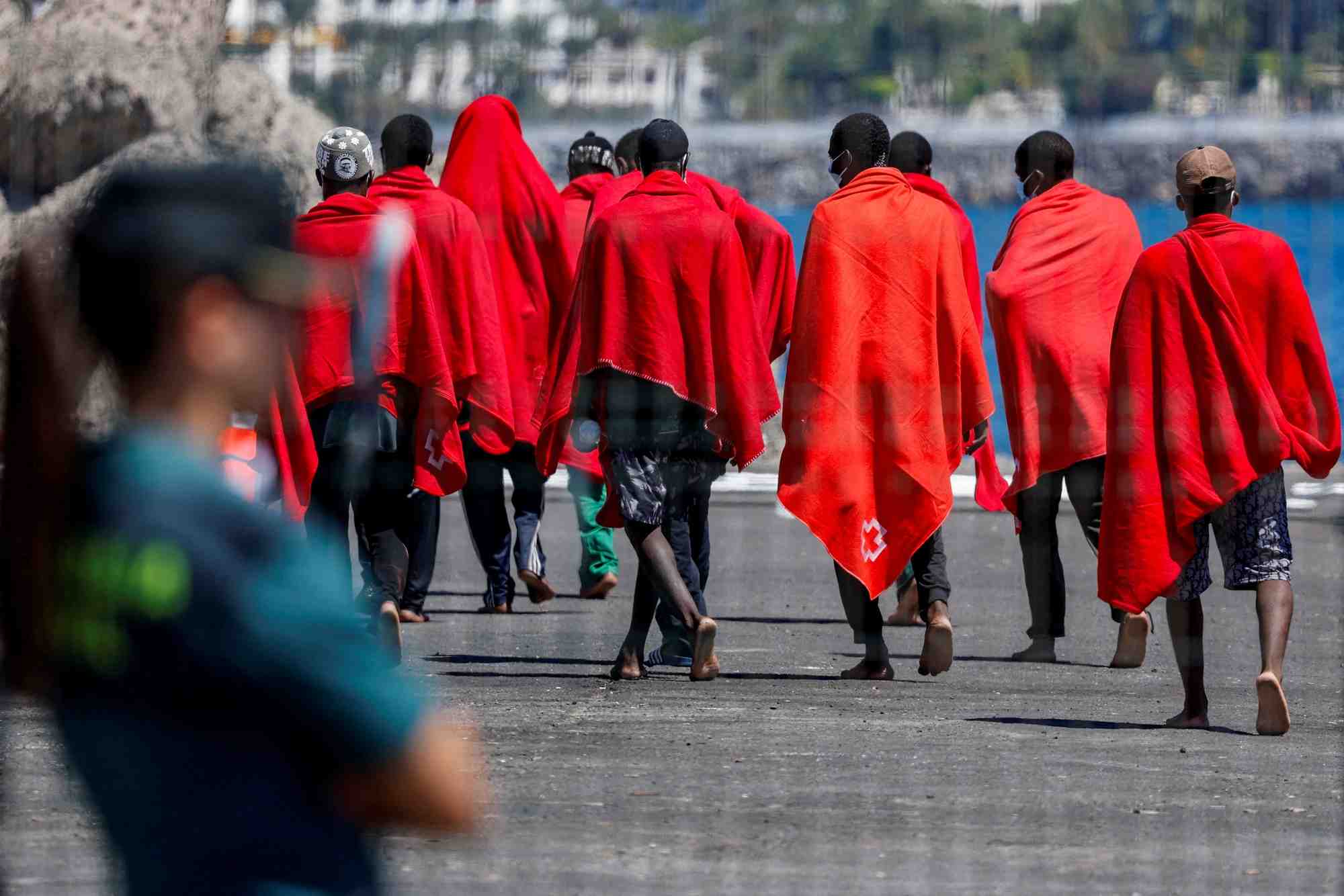 Des migrants se dirigent vers une tente de la croix-rouge apres avoir debarque d'un navire des garde-cotes espagnols, dans le port d'arguineguin.