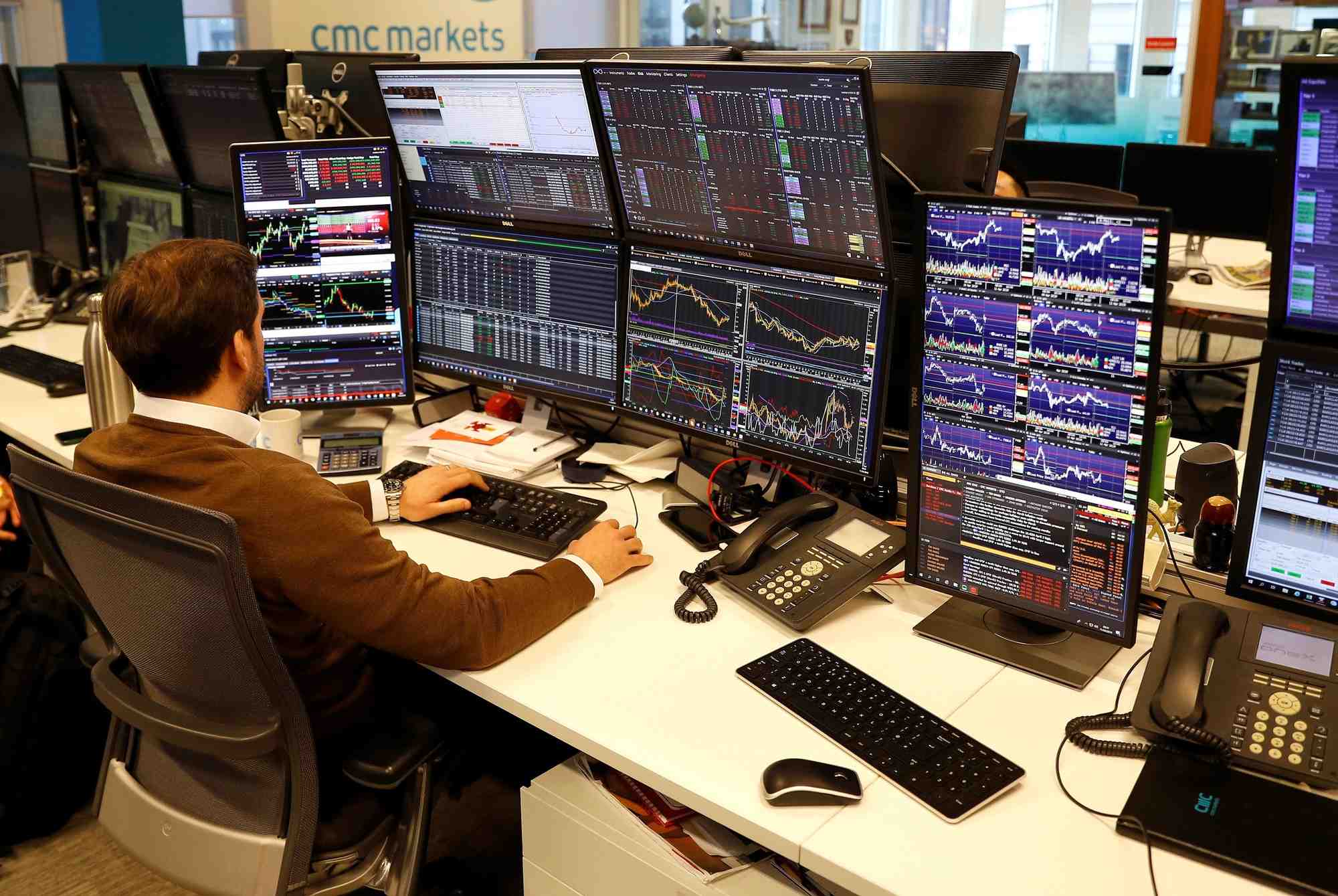 Un trader travaille a son bureau chez cmc markets a londres, en grande-bretagne