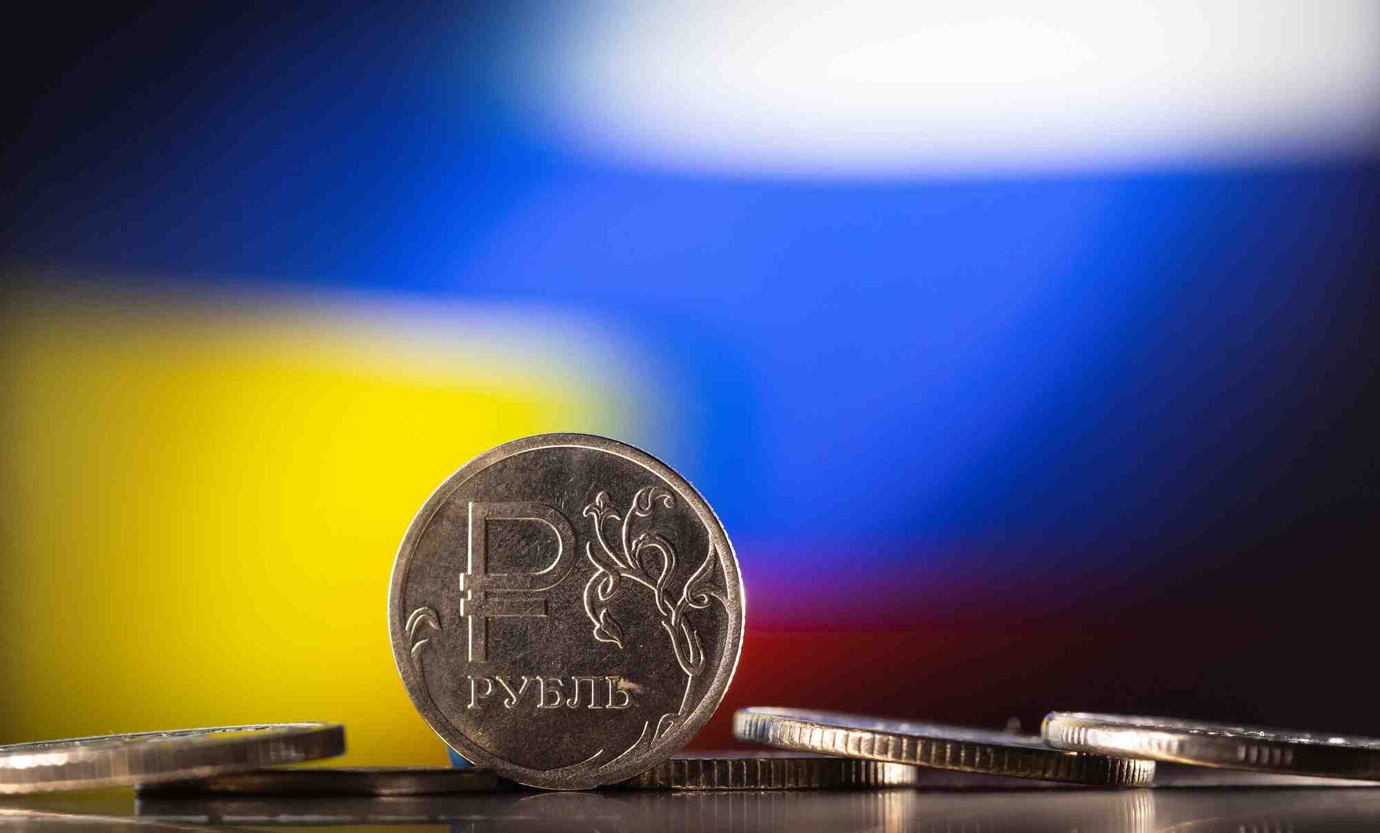 Image d'illustration montre des pieces en rouble russe devant des drapeaux ukrainiens et russes
