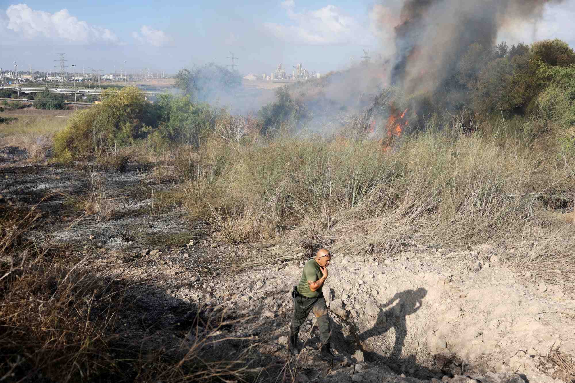 Un policier israelien marche a cote d'un cratere a l'interieur d'un point d'impact suite a une attaque de missiles en provenance du yemen.