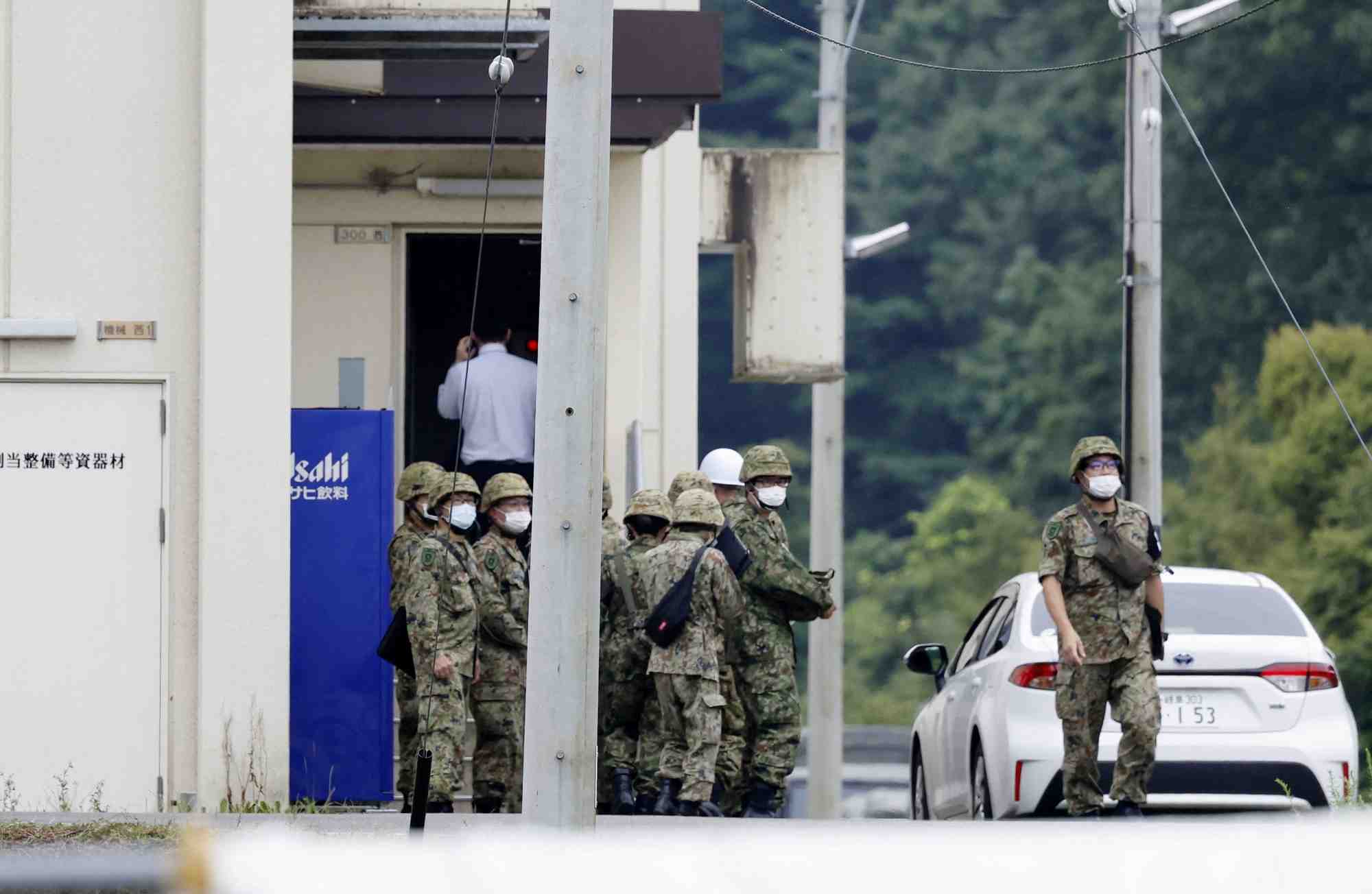 Des membres des forces d'autodefense japonaises (sdf) autour du champ de tir ou un adolescent a ete arrete pour tentative de meurtre
