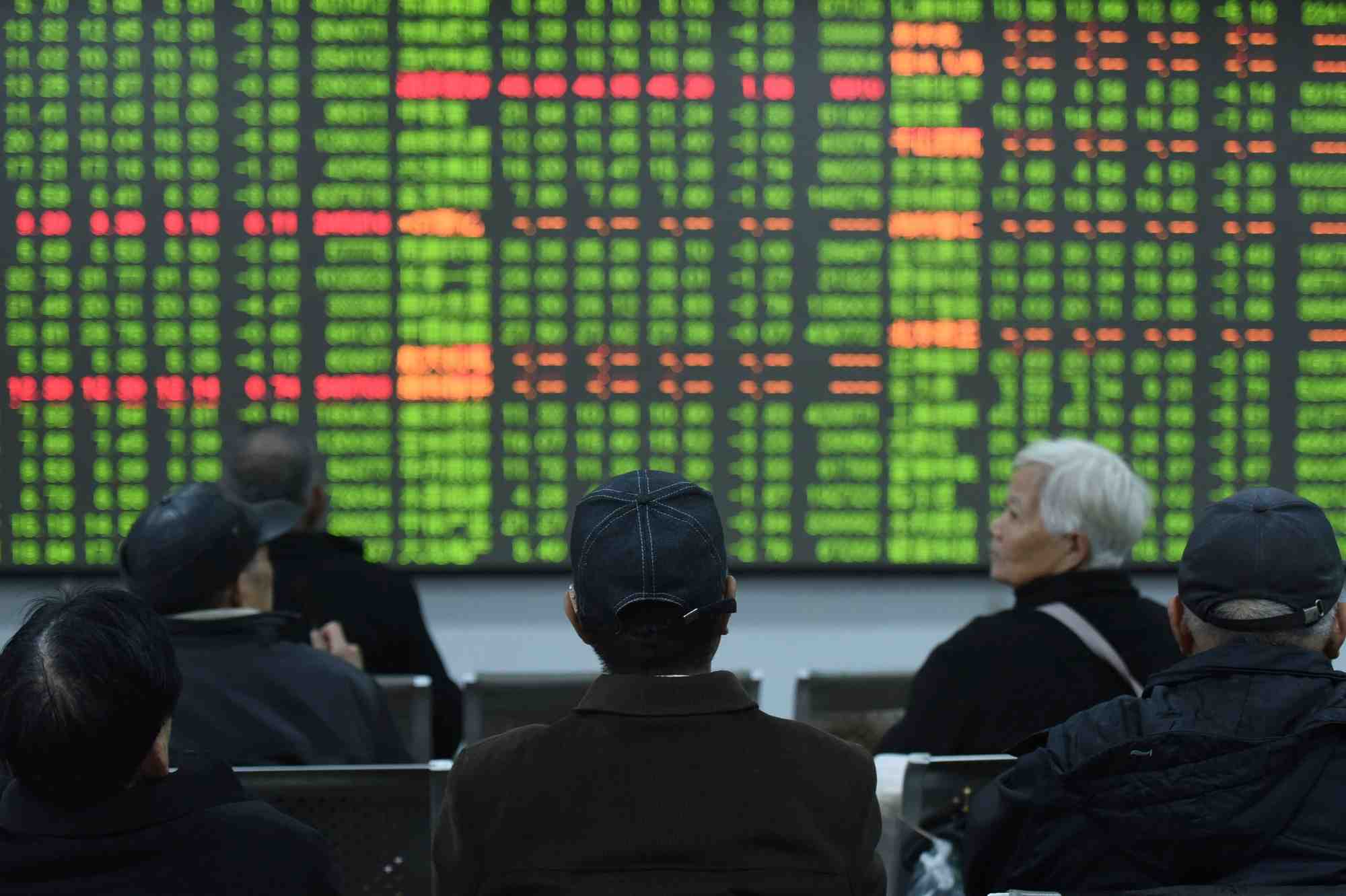 Les investisseurs se tiennent devant un tableau affichant des informations dans une maison de courtage lors du premier jour de negociation en chine depuis le nouvel an lunaire 2020 a hangzhou, dans la province chinoise du zhejiang