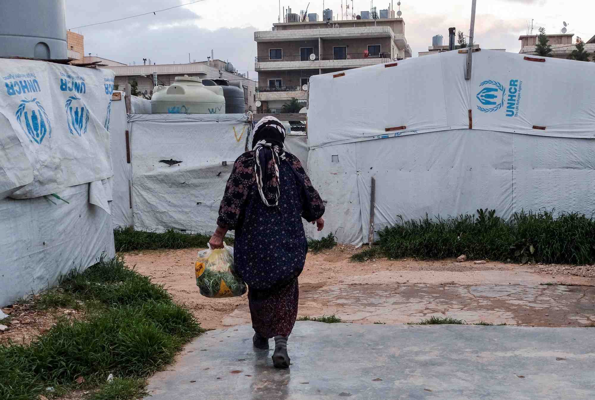 Un refugie syrien marche pres de tentes dans un campement informel, a al-marj au liban