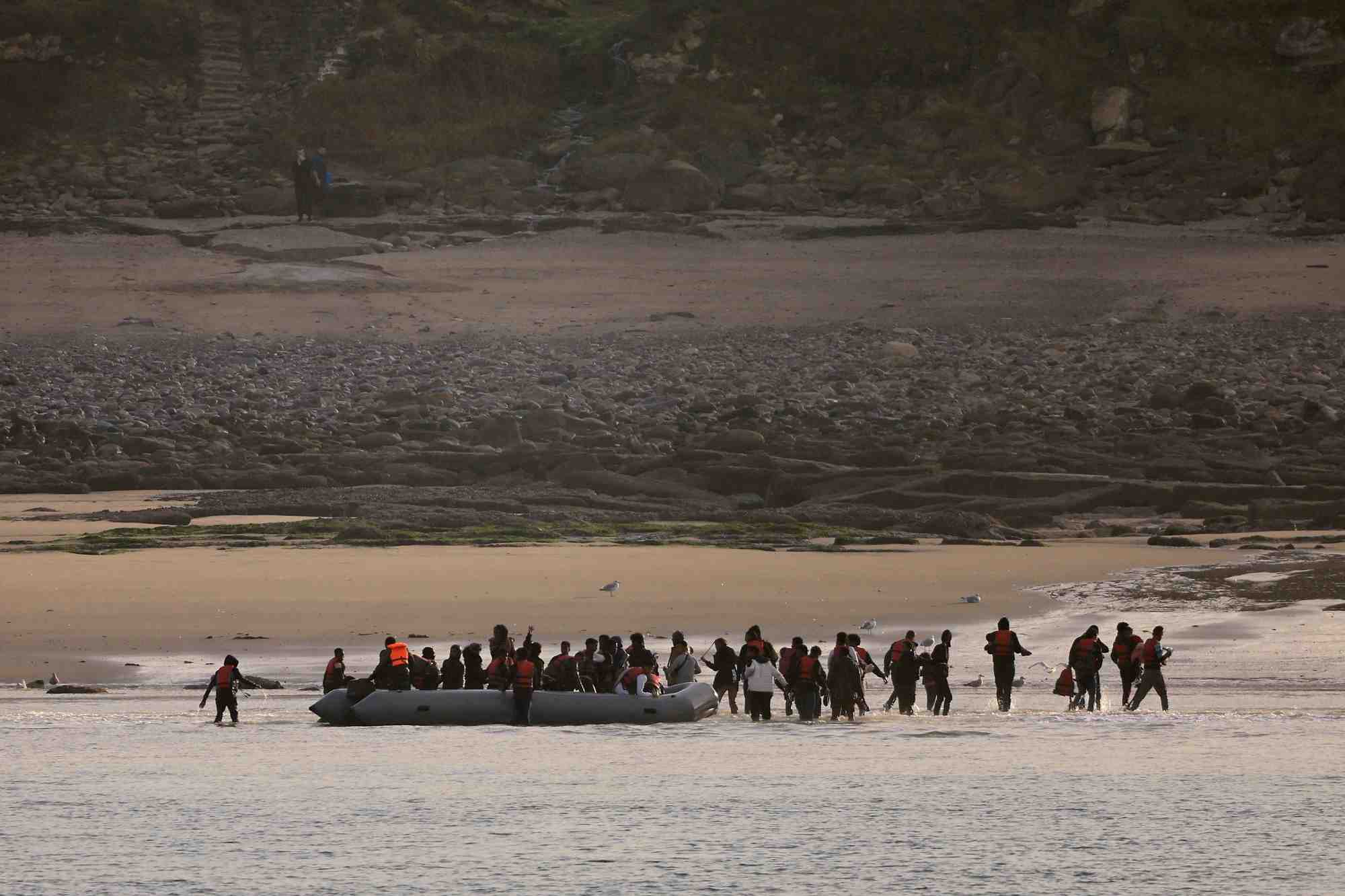 Un groupe de migrants debarque d'un canot pneumatique sur la plage de le portel, dans le nord de la france