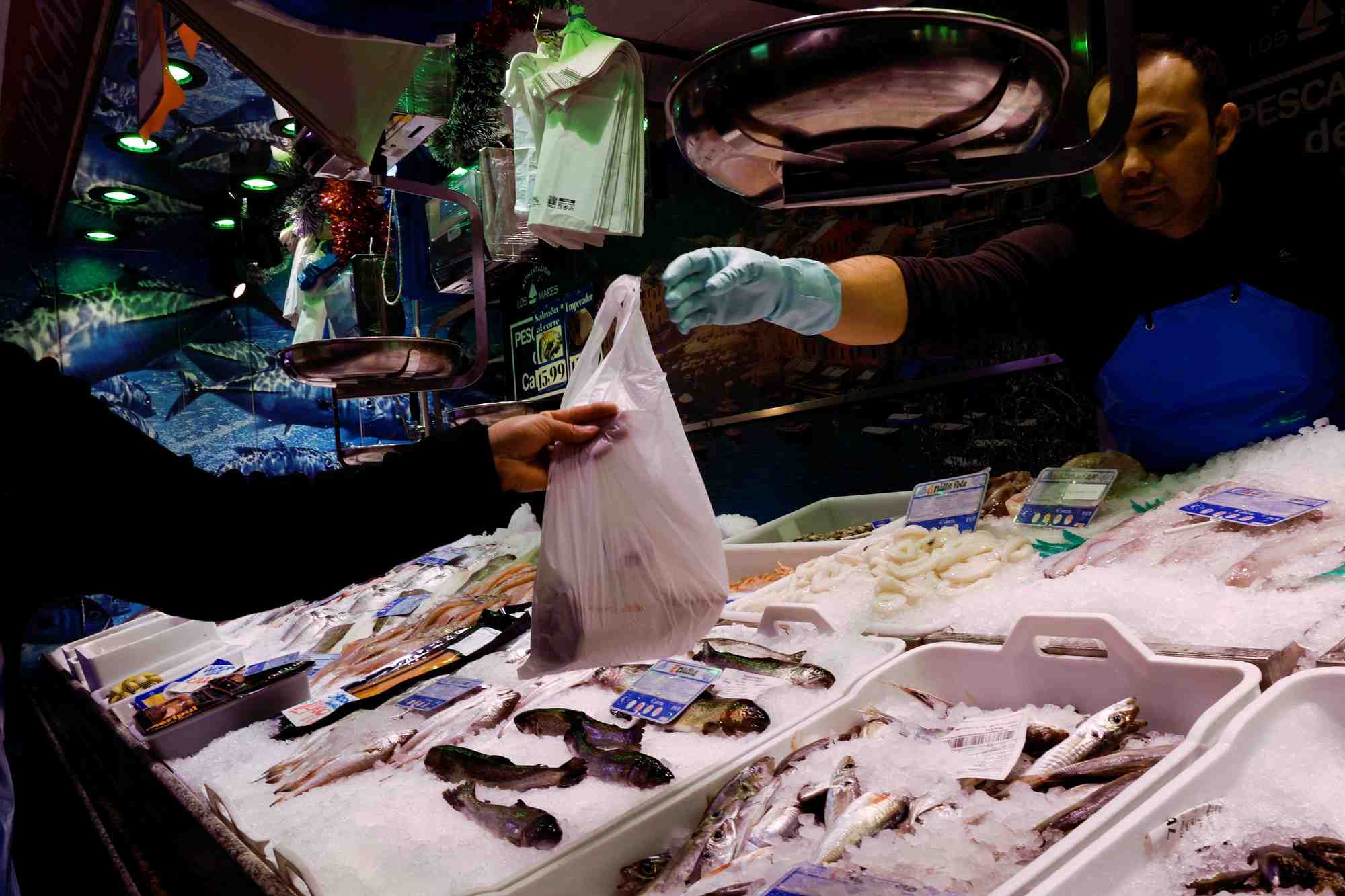 Un poissonnier tend un sac a un client dans un supermarche a madrid