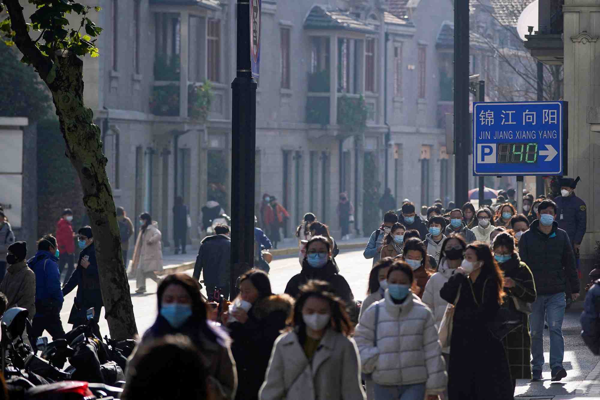 Des personnes portant des masques de protection marchent dans une rue a shanghai, en chine