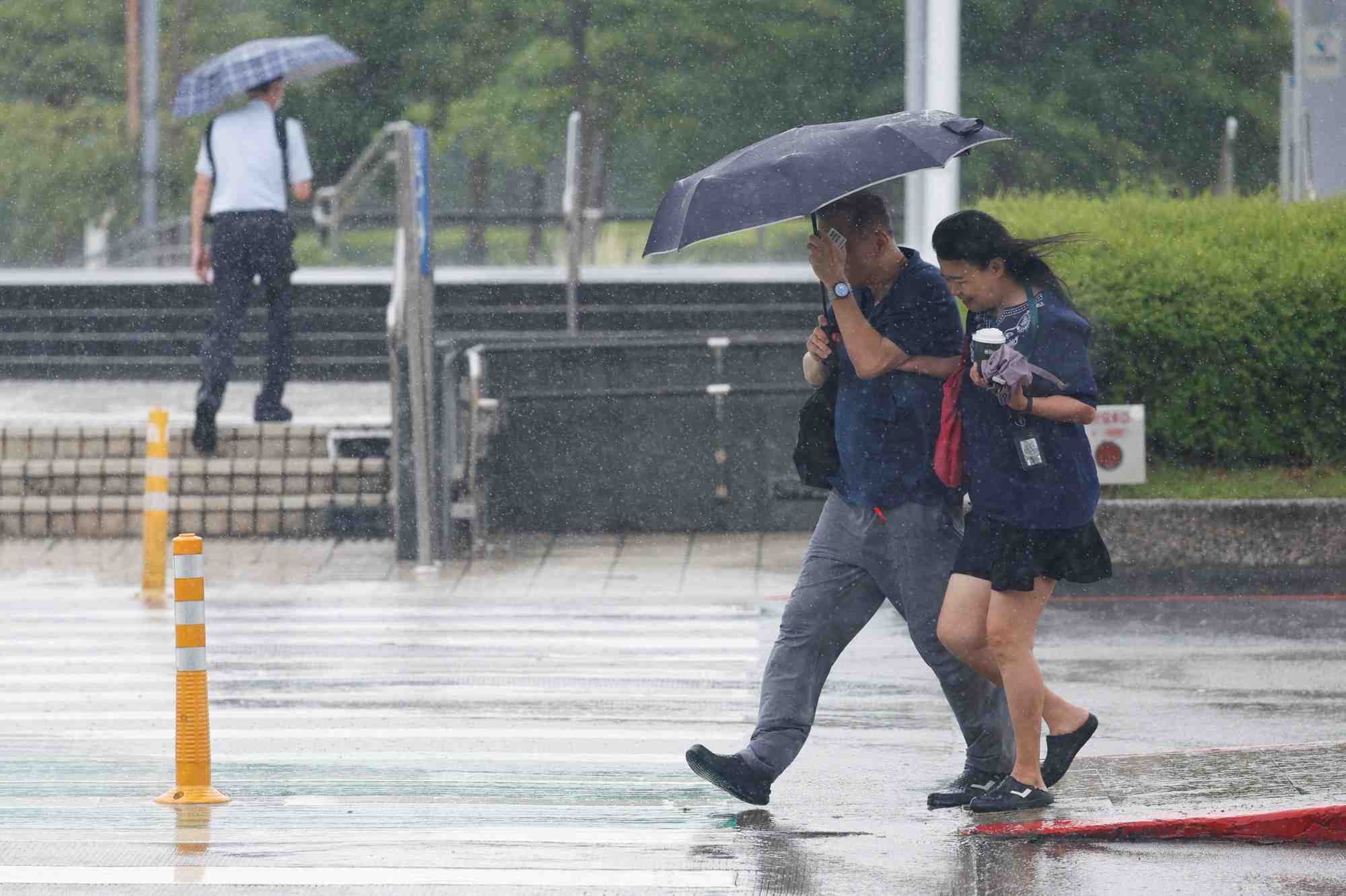 Des personnes sous la pluie devant l'aeroport songshan de taipei