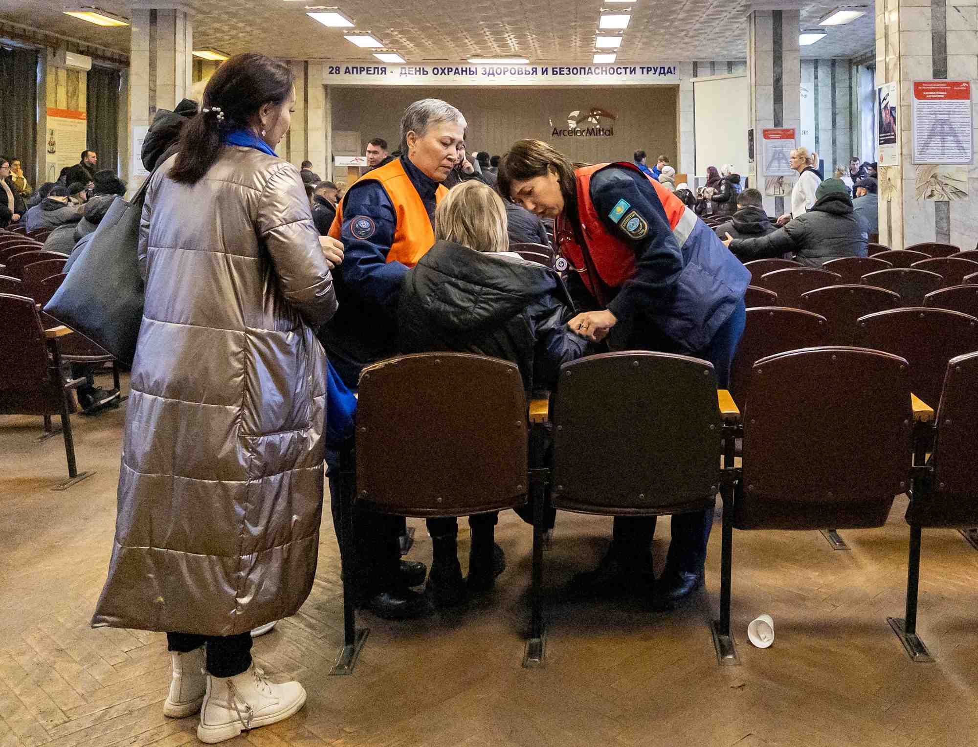 Une femme est aidee a la mine de charbon de kostenko, alors que des parents de mineurs se rassemblent lors d'une operation de sauvetage a la suite d'un incendie dans la mine, a karaganda
