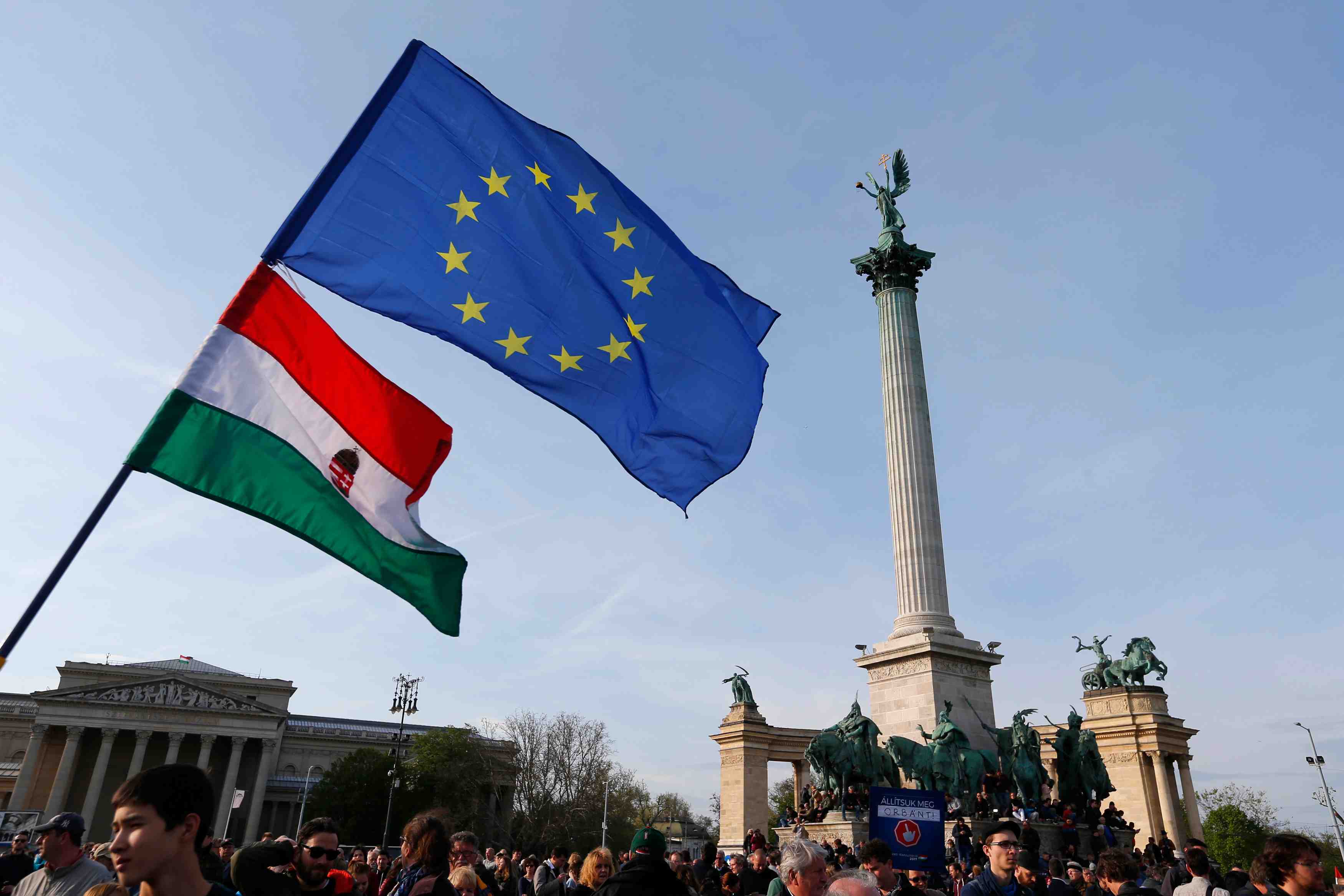 People wave hungarian and european union flags as they protest in heroes’ square against a new law that would undermine central european university in budapest