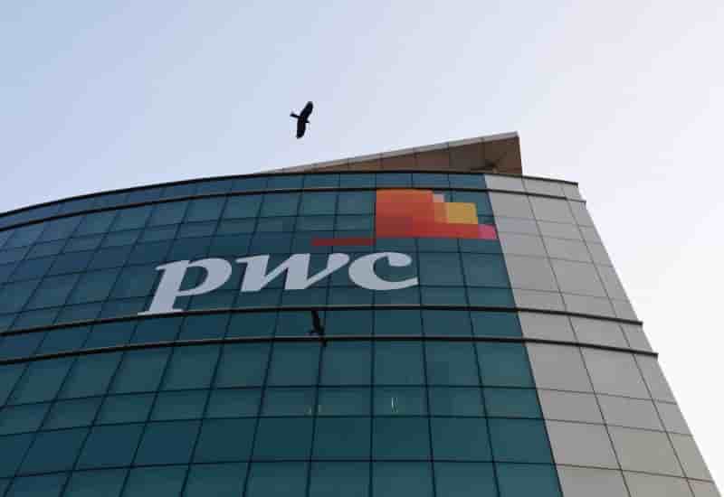 A bird flies past the logo of price waterhouse installed on the facade of its office in mumbai