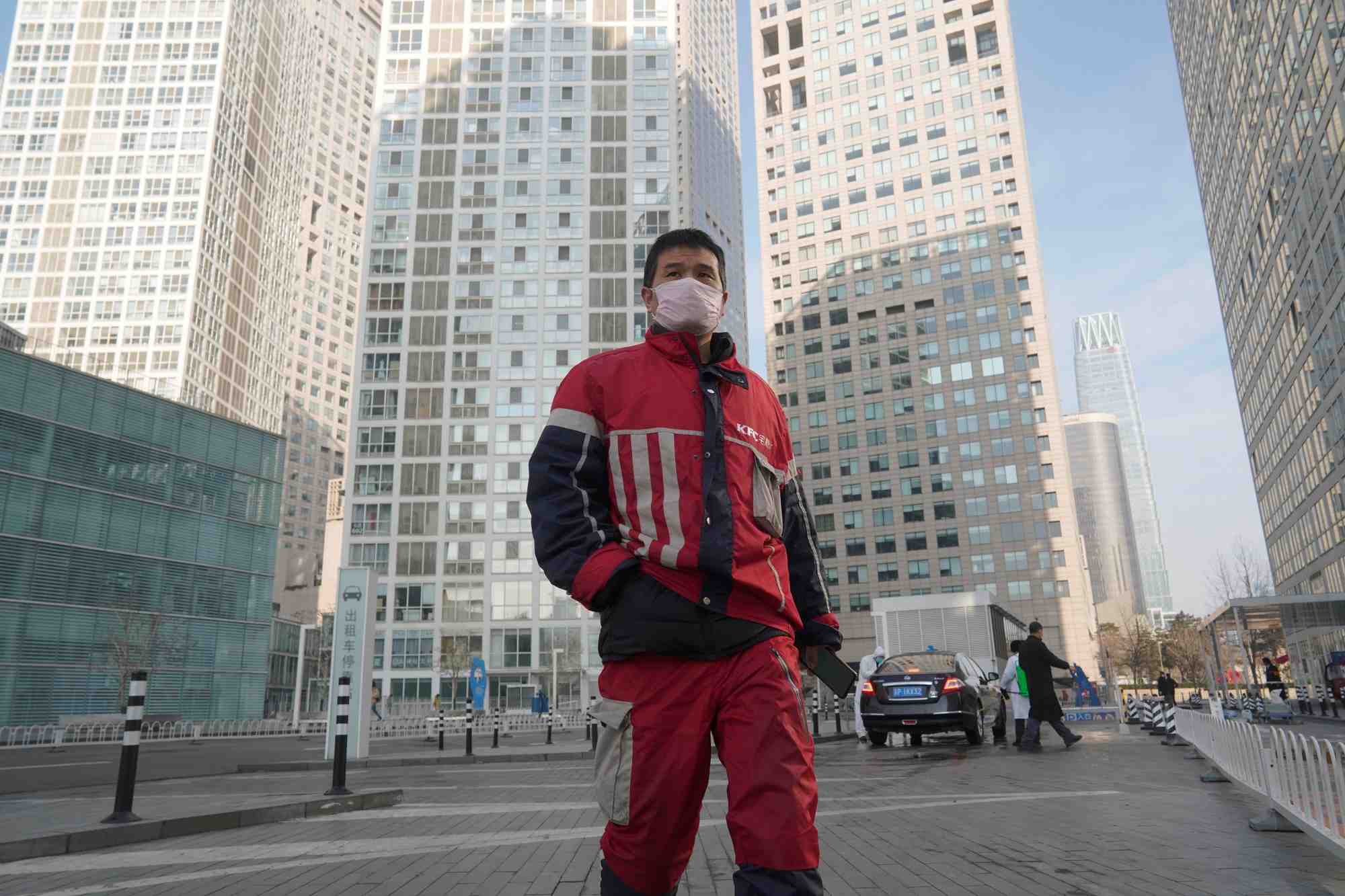 Coronavirus / Covid-19 : un livreur KFC marche dans un complexe commercial situé dans le quartier des affaires de Beijing en Chine