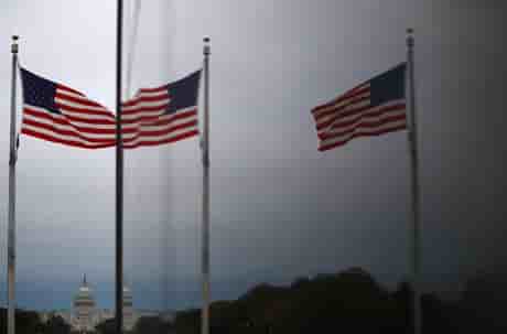 Le capitole des etats-unis et les drapeaux americains se refletent dans une fenetre a washington