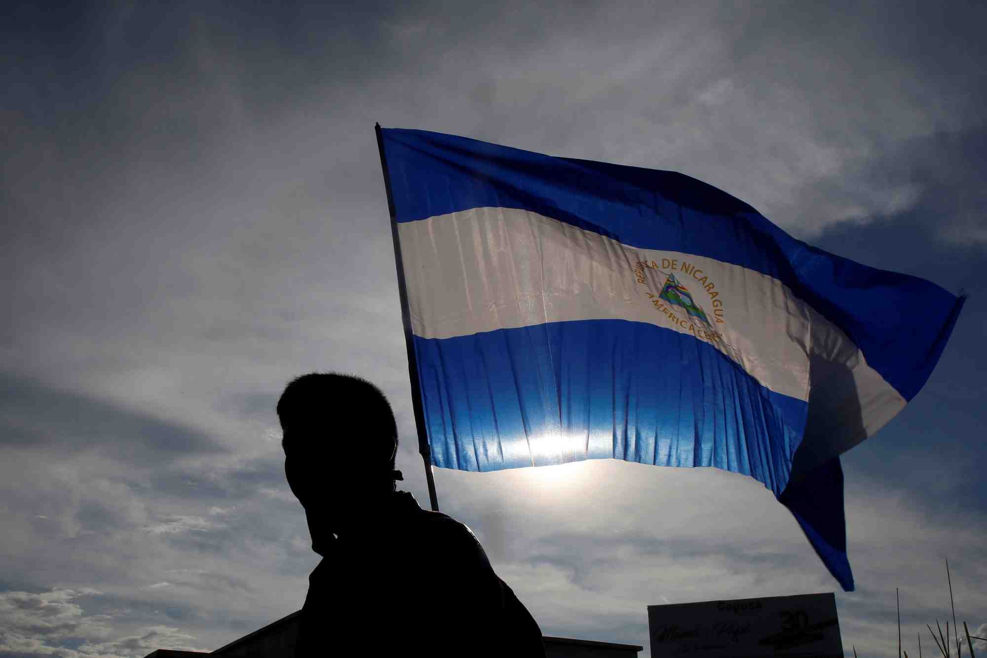 Une personne brandit un drapeau national nicaraguayen lors d'une manifestation a managua