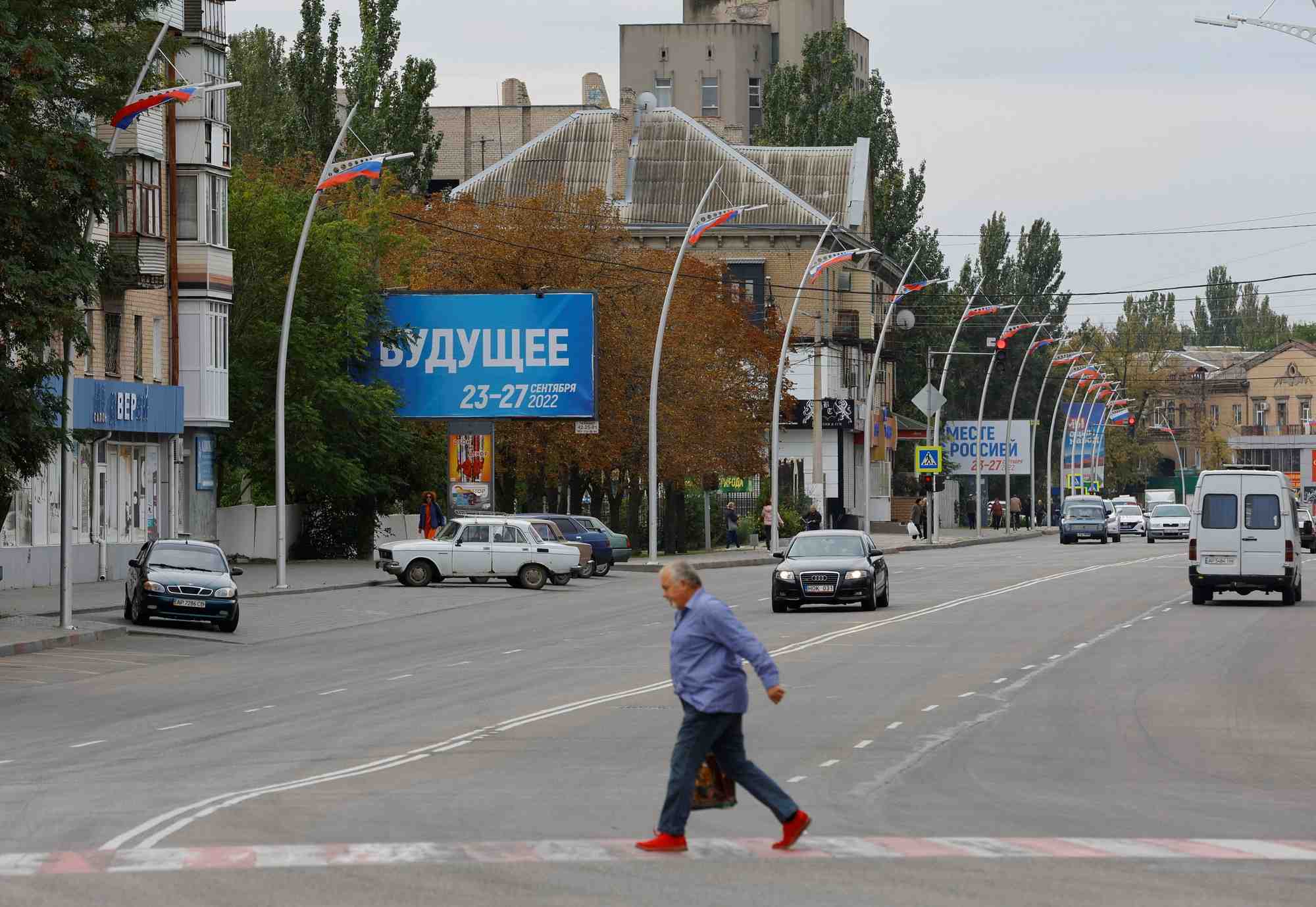 Un homme marche devant des panneaux au sujet d'un referendum sur le rattachement a la russie des regions ukrainiennes controlees par la russie