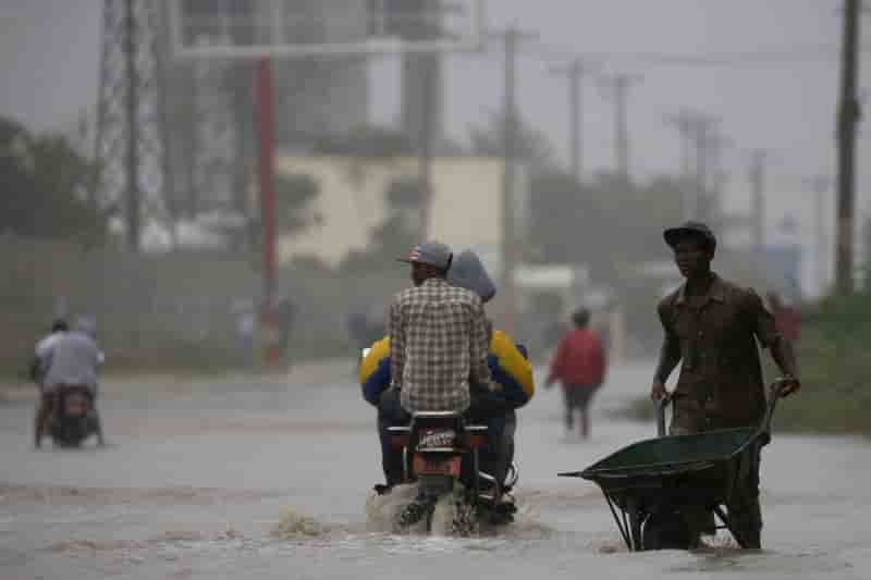 A man pushes a wheelbarrow as he wades across a flooded street while hurricane matthew passes through port-au-prince, haiti