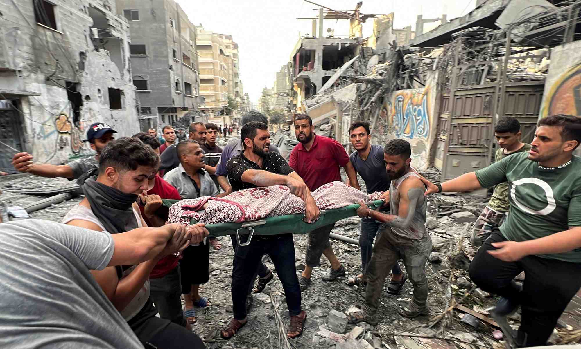 Des palestiniens portent un blesse sur le site de frappes israeliennes sur des maisons, dans la ville de gaza